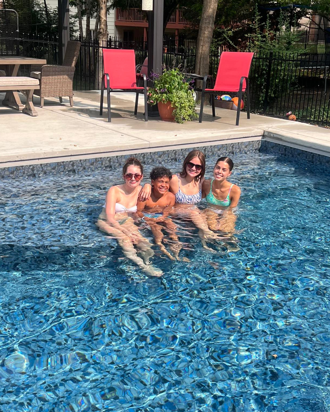 Kids sitting on a custom bench in an inground pool built by Super Pools in Wichita Kansas