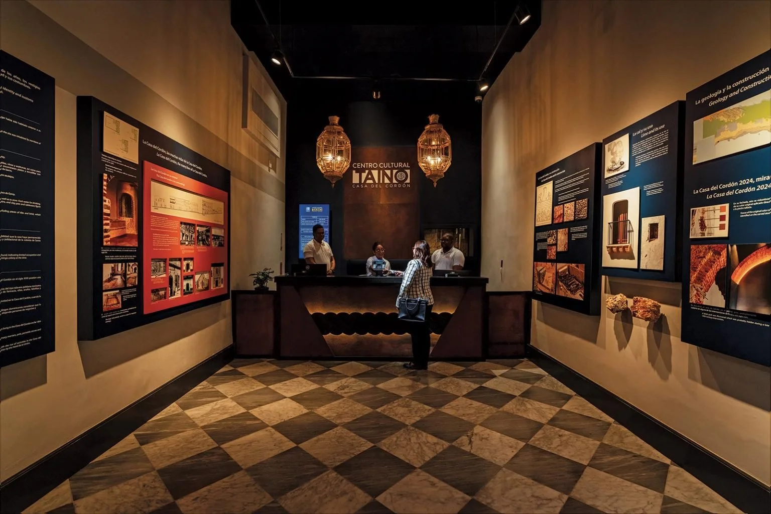 Reception desk and museum exhibits at Centro Cultural Taíno Casa del Cordón, featuring marble checkered floors and informative wall panels in Zona Colonial Santo Domingo.