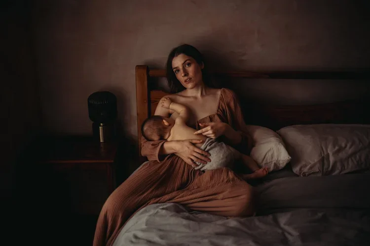Mother breastfeeding baby in a dark room