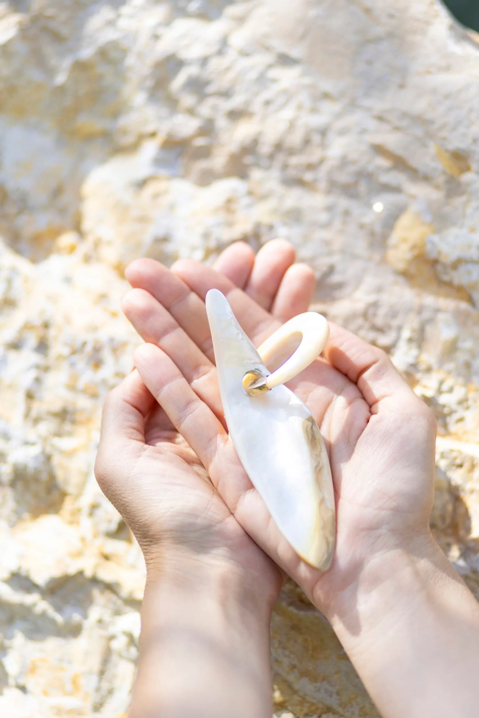 coquillage au creux de la pomme de deux mains sur le sable face au soleil pour montrer que l'énergie est une ressource précieuse pour notre vie