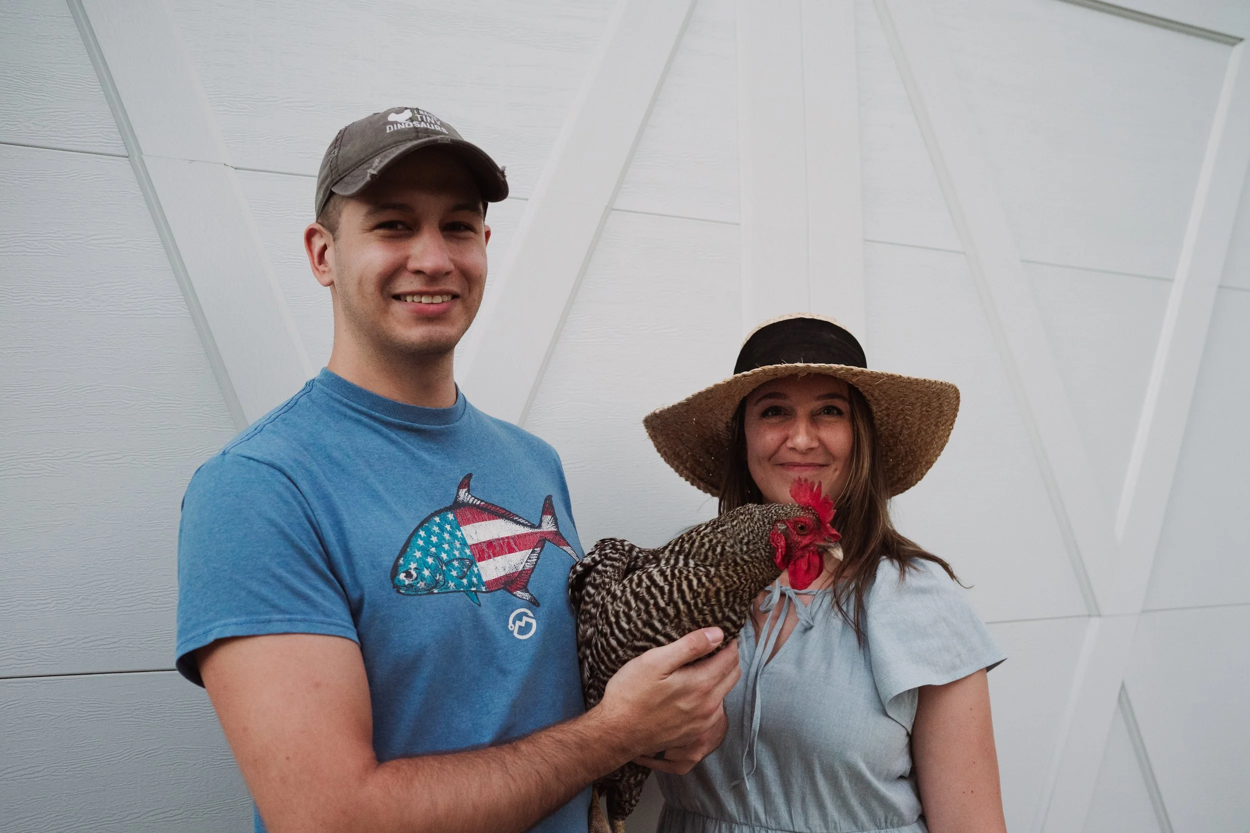 man and woman in front of barn door holding rooster