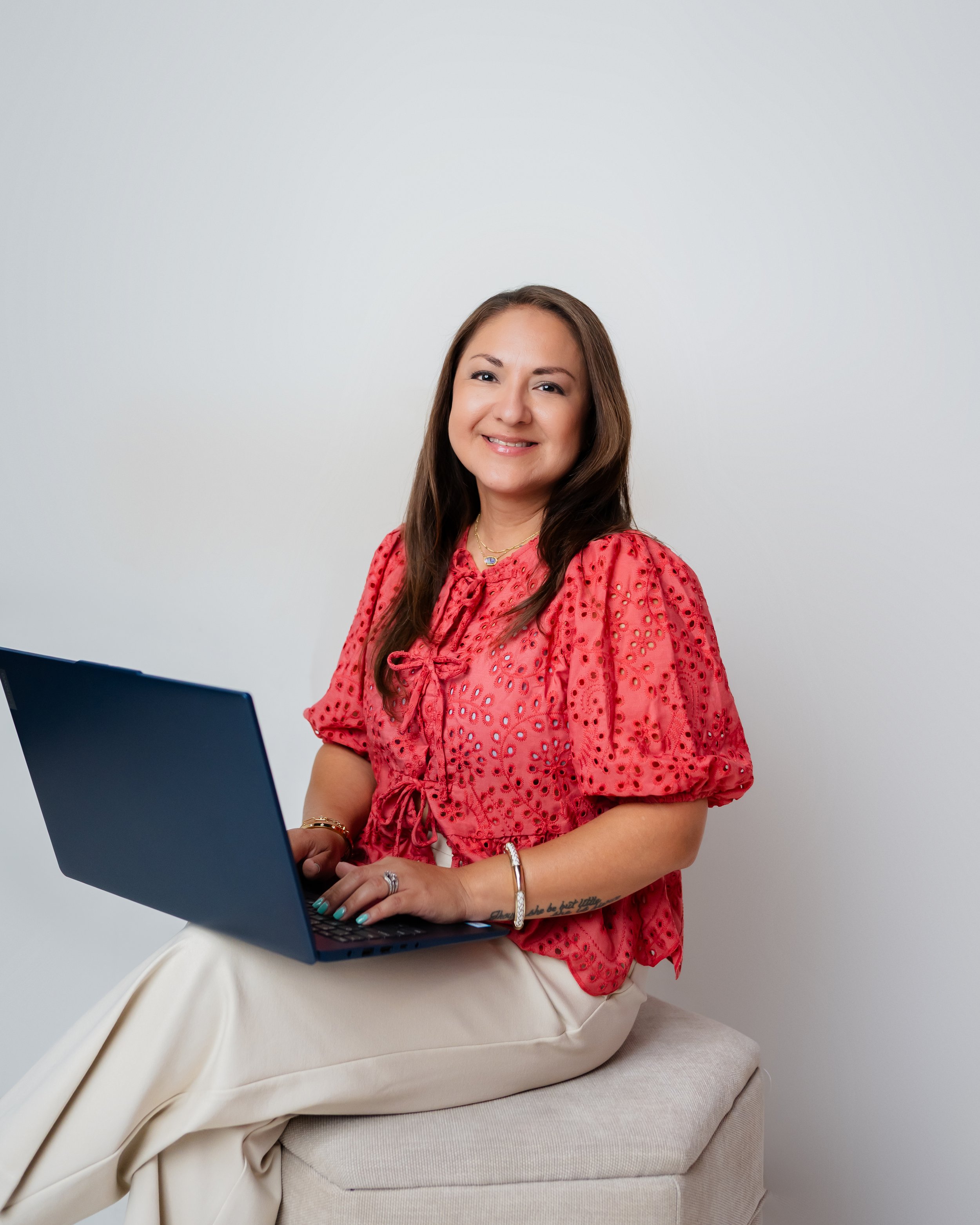 Valerie Rivera working on her laptop while seated on a couch.