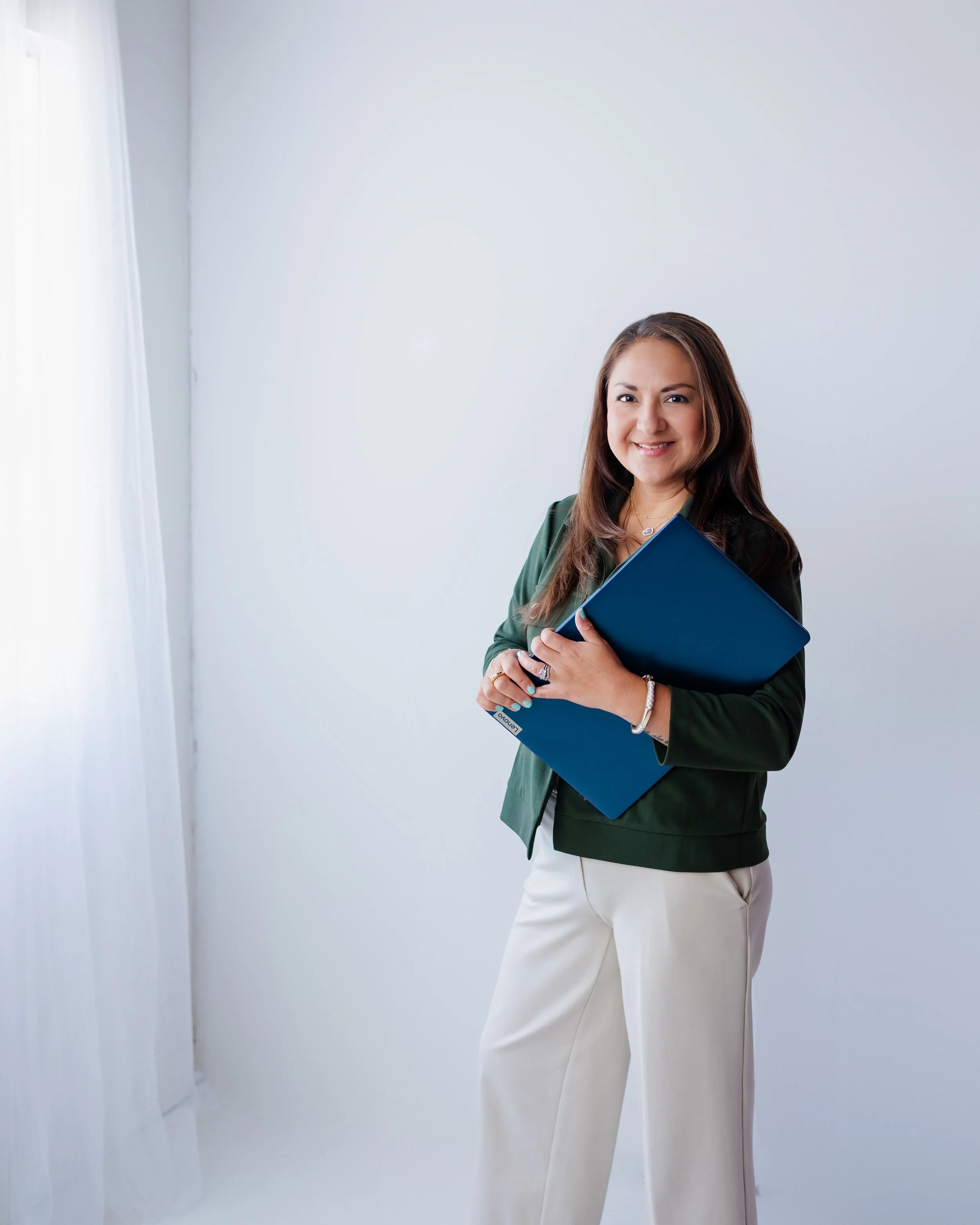 Valerie Rivera, therapist and private practice coach, standing with a blue laptop.