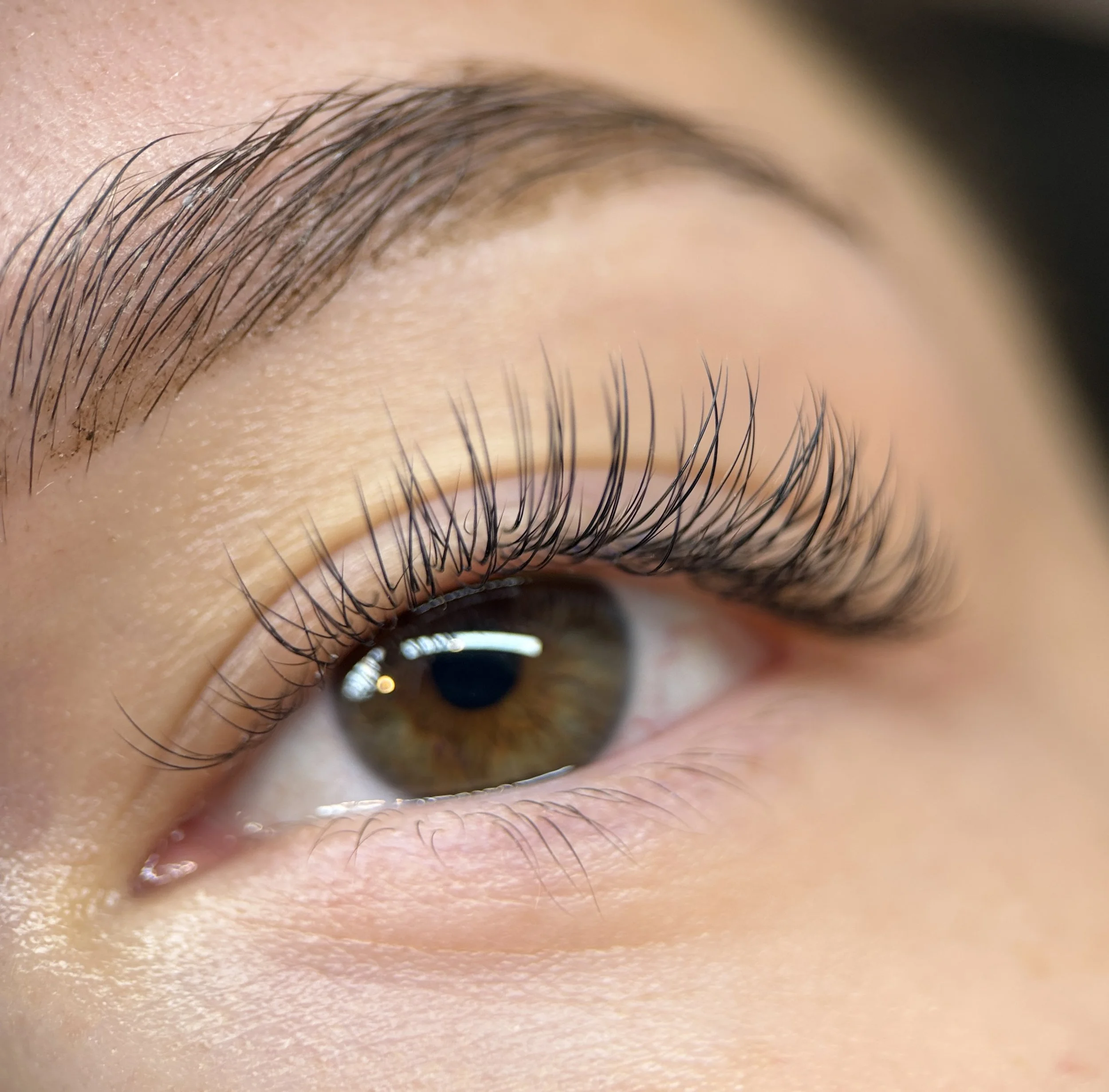 Close-up of a person's closed eye with long eyelashes and smooth skin.