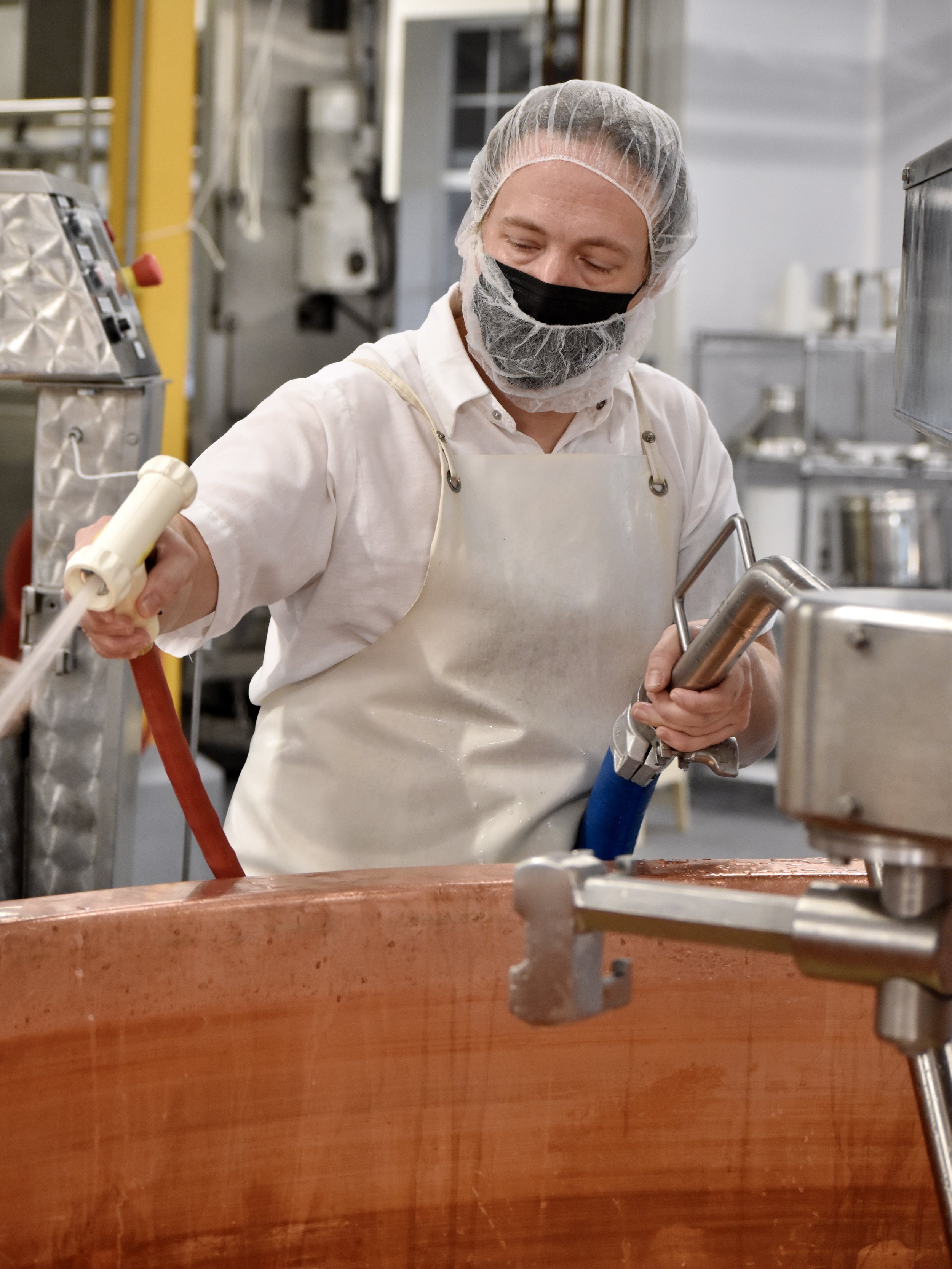  Cheesemaker spraying down copper vats during a cheese make  