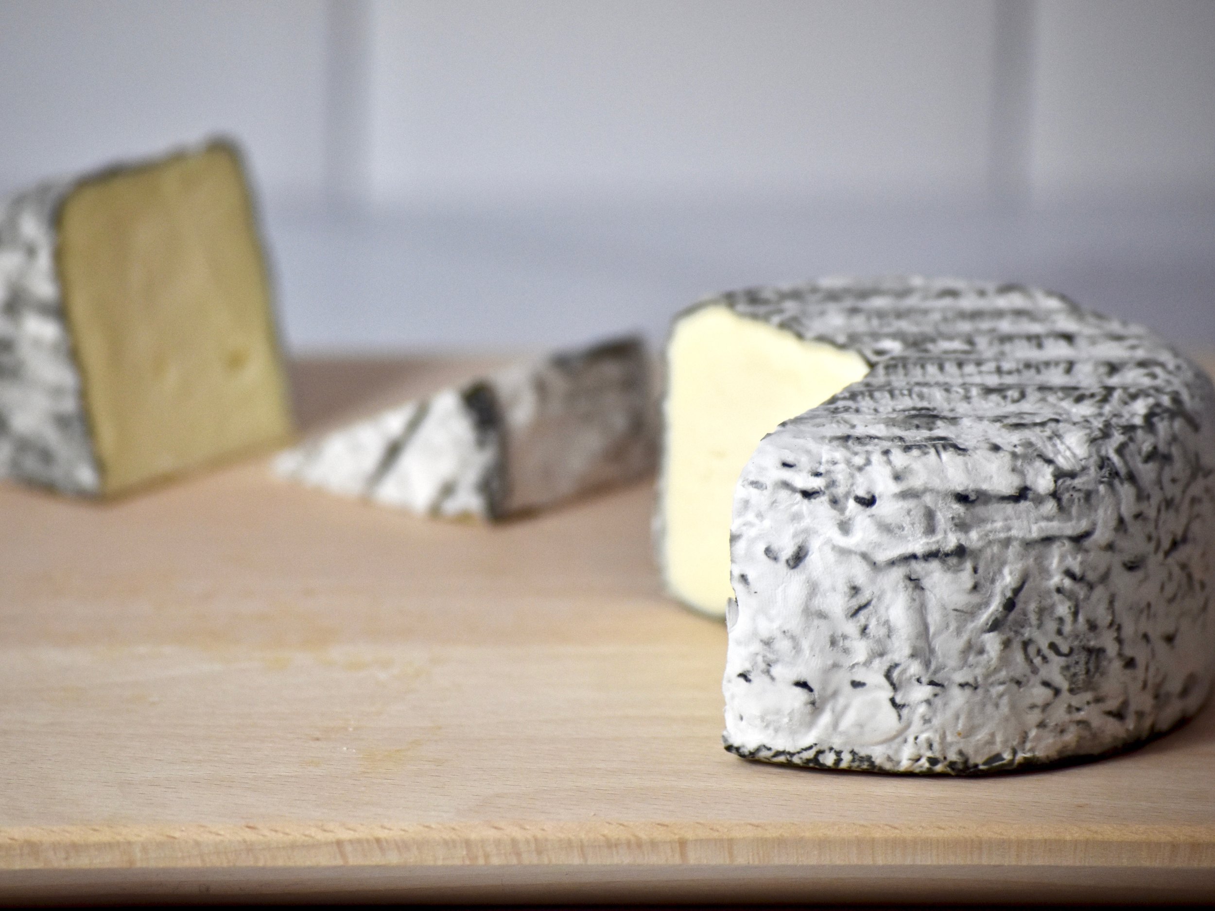  A wheel of ash-ripened cheese on a cutting board  