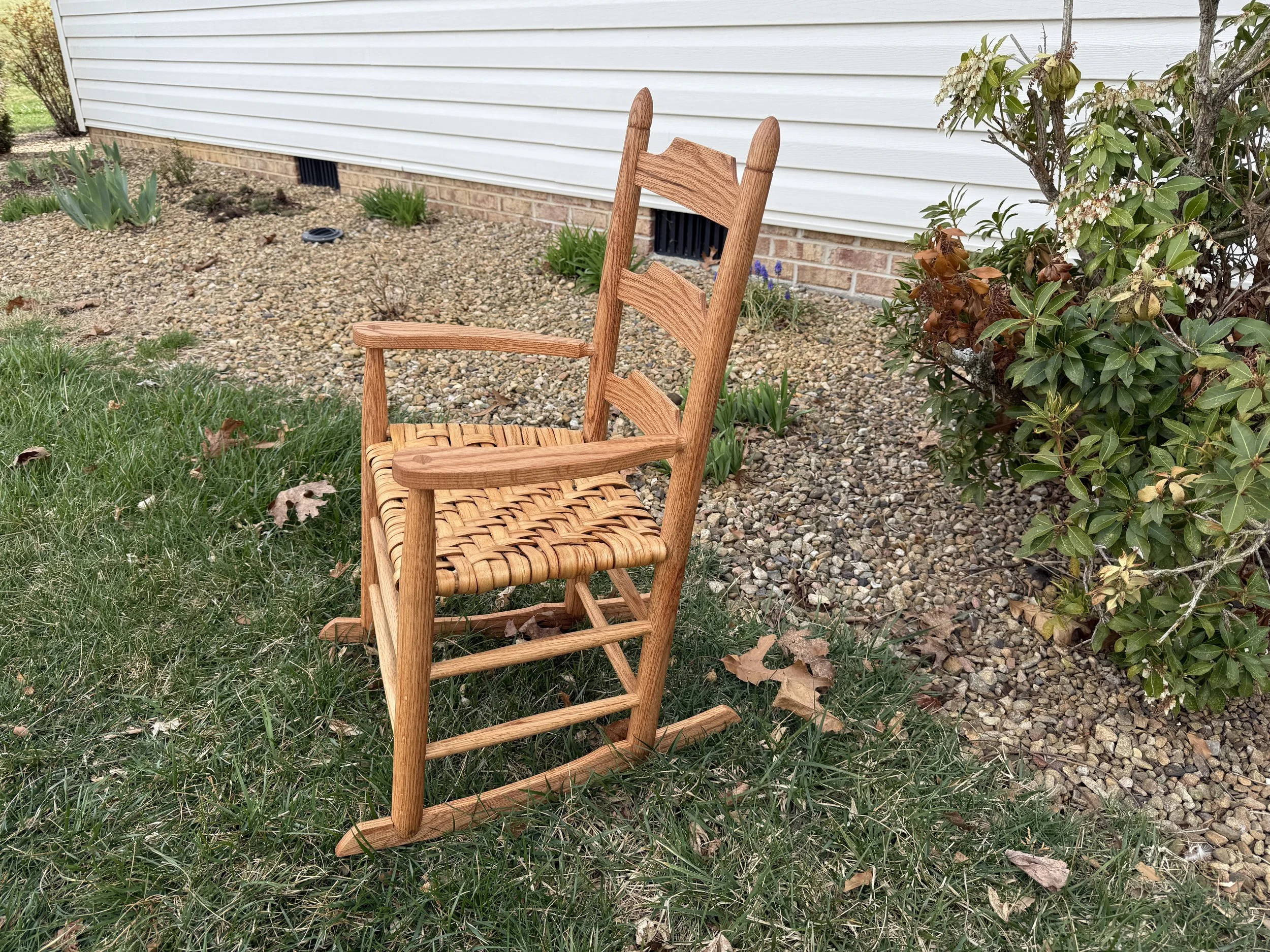 Child-sized rocker in red oak with hickory bark seat.