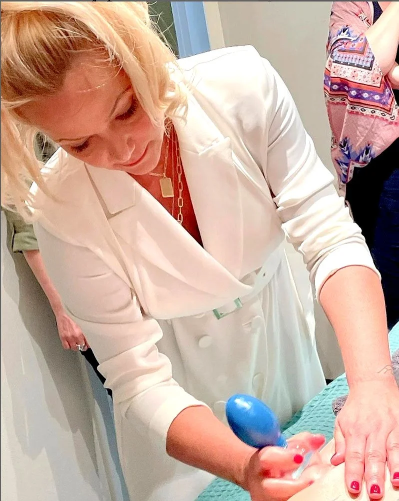 vrouw in witte jas die een medische procedure uitvoert met een blauwe instrument, mogelijk een spuit, op een patiënt.