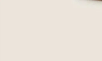 A blank, off-white or beige wall with a small black object or mark in the top right corner.