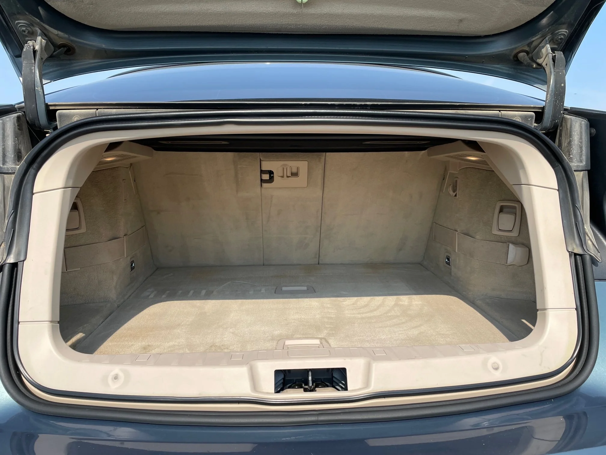 Open car trunk with beige interior, showing spacious cargo area and rear interior panels.