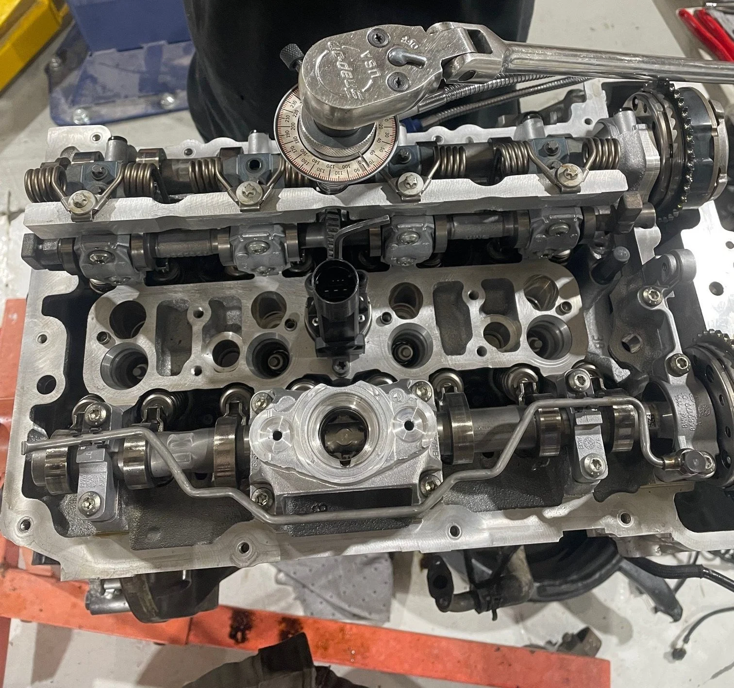 A partially disassembled car engine with a rockers, camshaft, and other engine components visible.