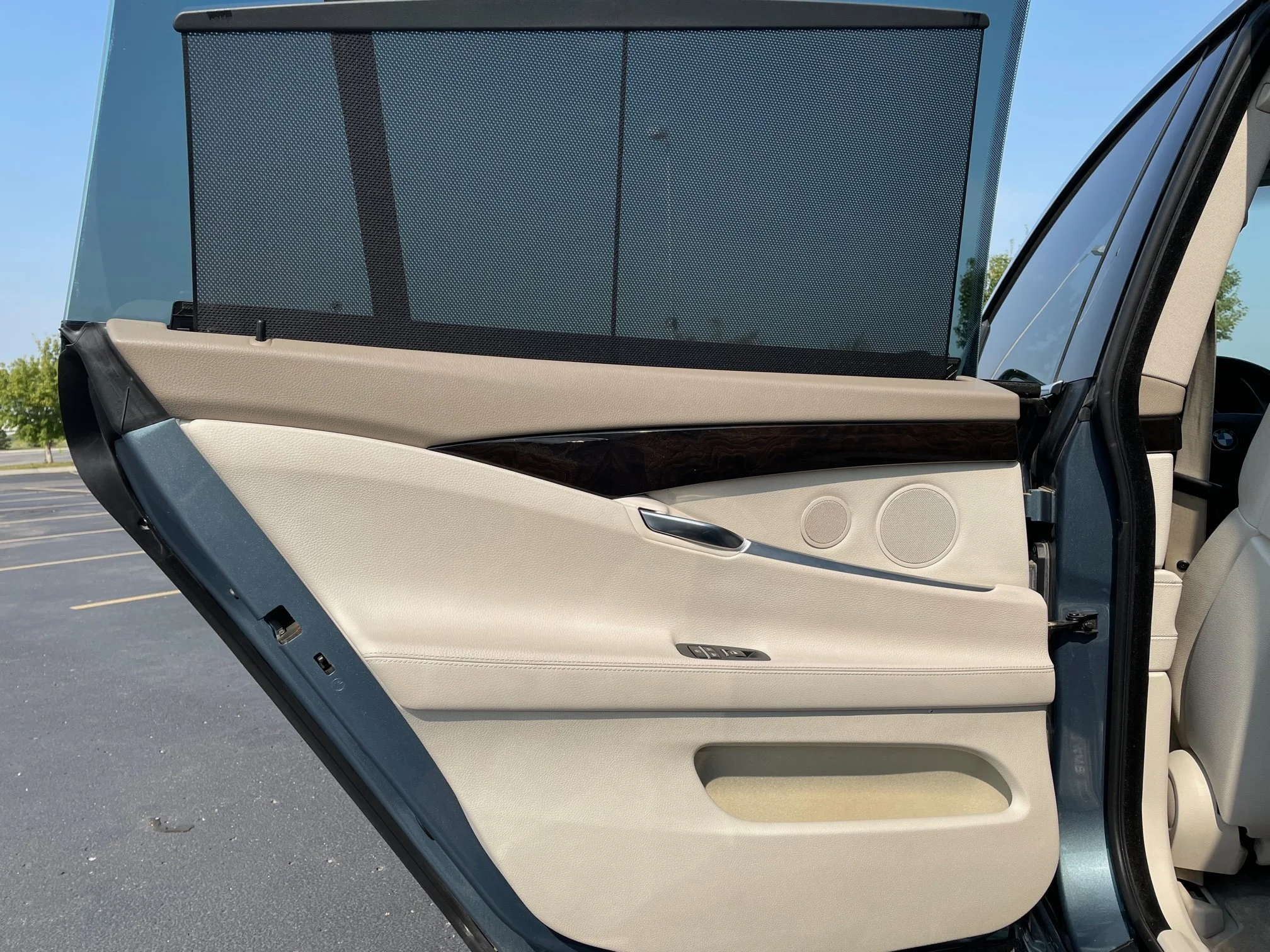 The interior of a car door featuring beige and black panels, a silver door handle, and built-in round speaker grilles.