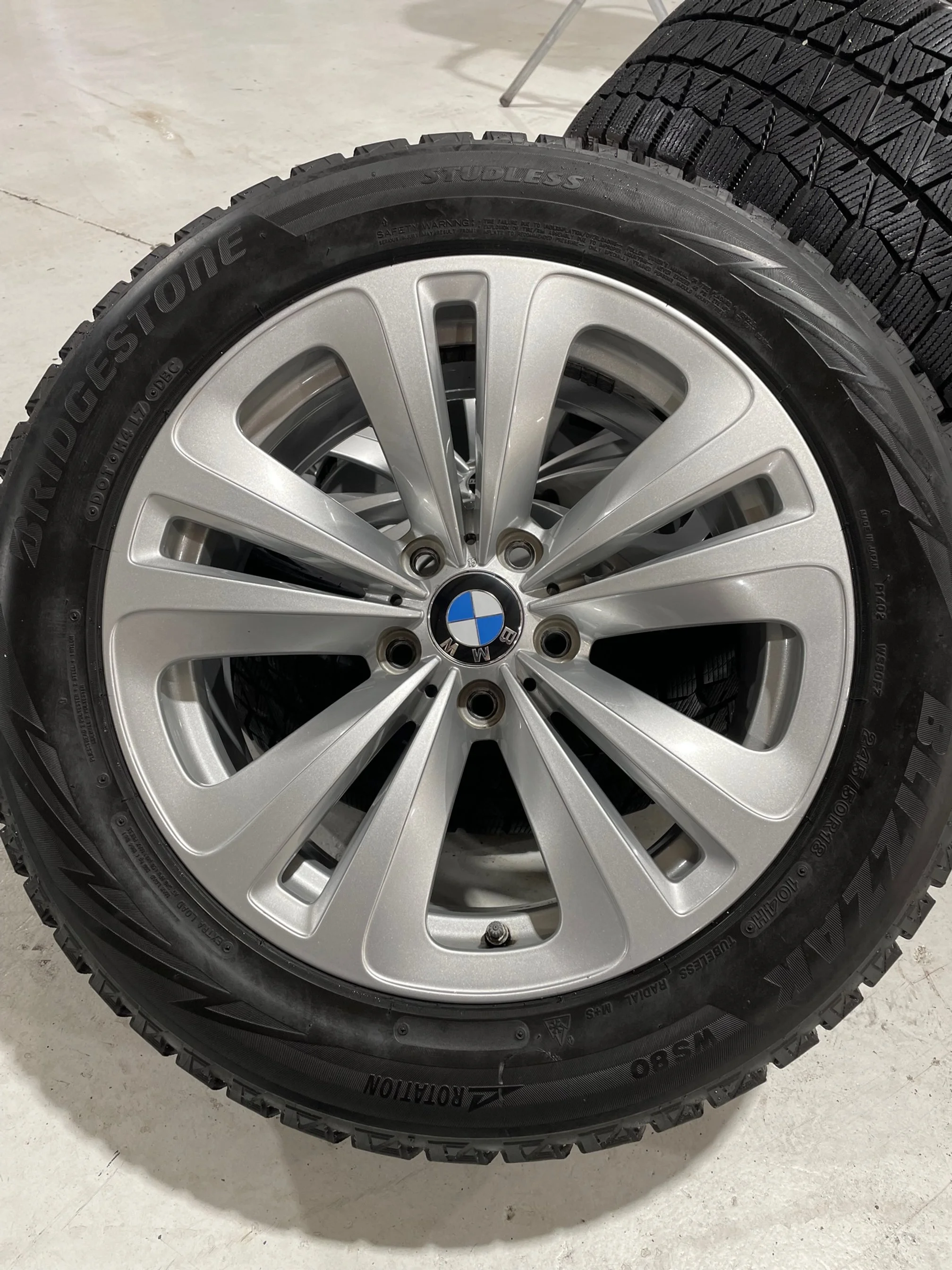 Close-up of a BMW wheel with a tire mounted, placed on a concrete floor.
