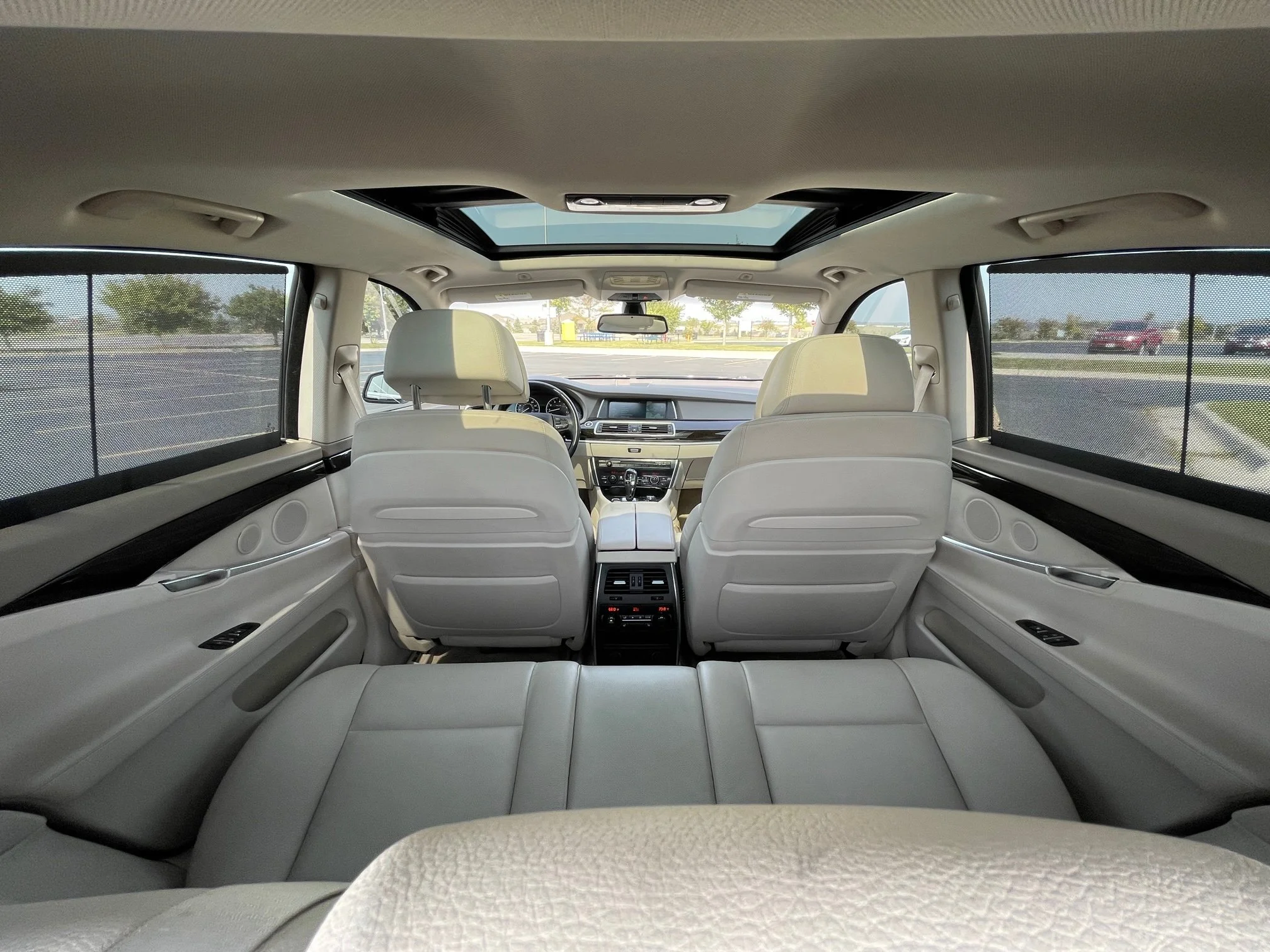 Interior of a luxury vehicle showing beige leather seats, a panoramic sunroof, and tinted windows.