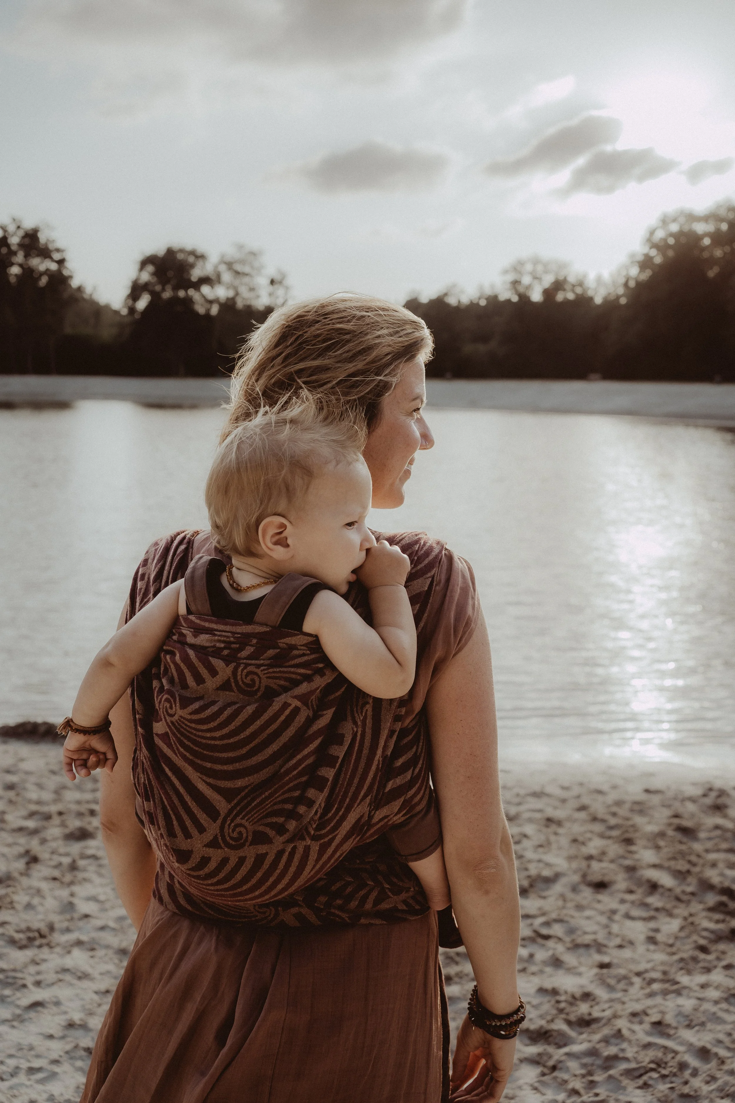 Vrouw met kind in draagdoek in de natuur bij het water. branding fotografie draagdoek draagconsulente.