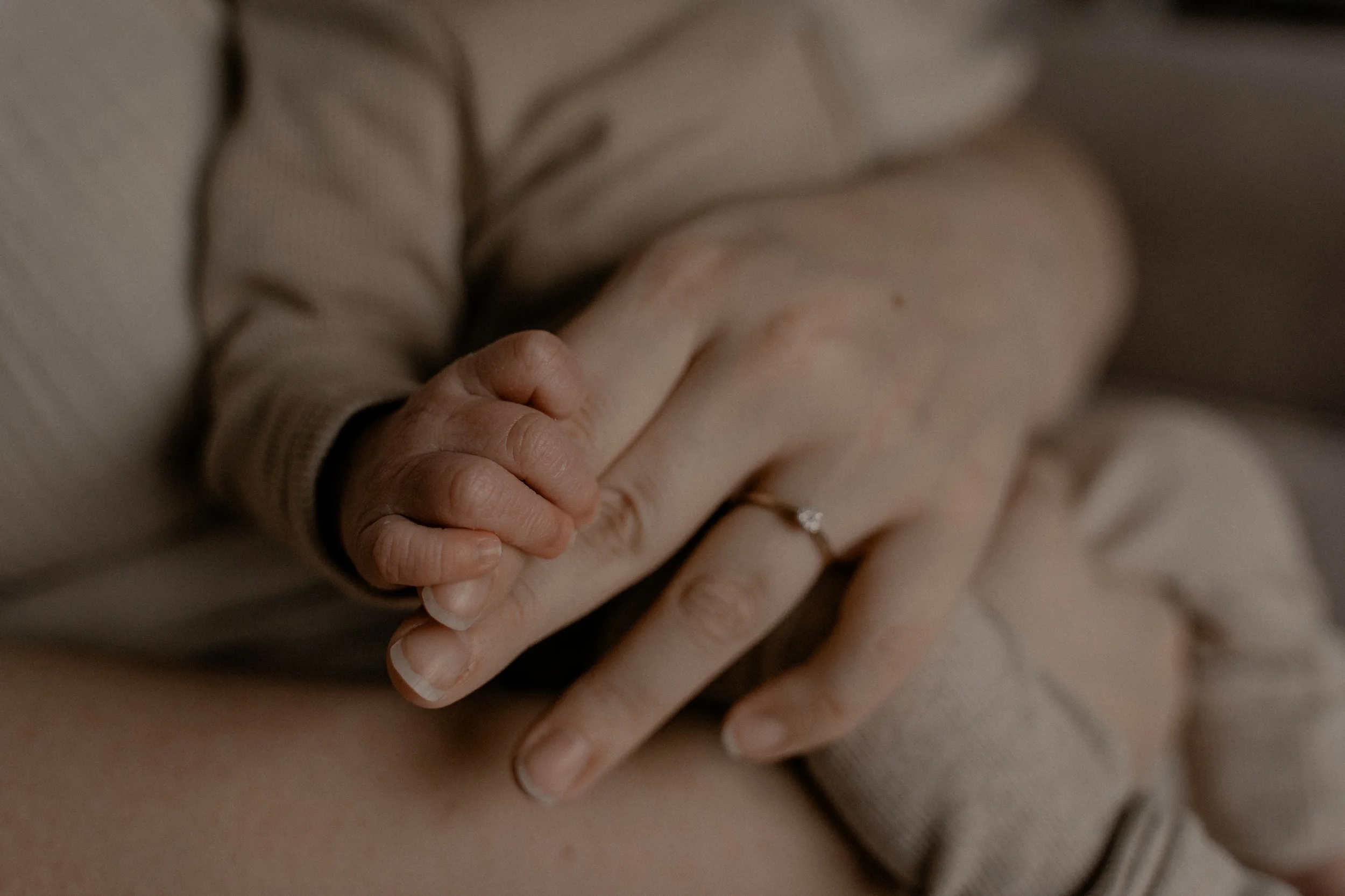 Baby handje houdt hand vast van mama. Detail foto newborn fotoshoot.