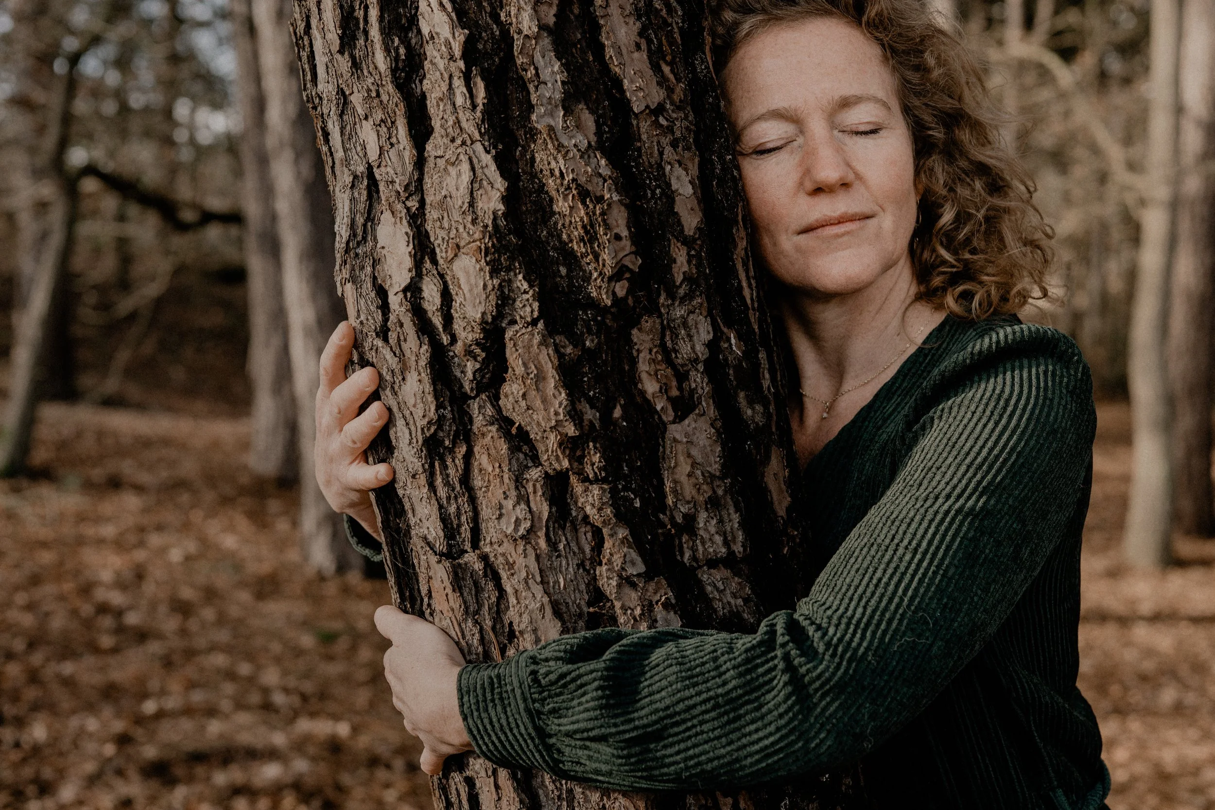 Vrouw in de natuur houdt een boom vast, aarden, coaching, personal branding fotografie assen Drenthe.