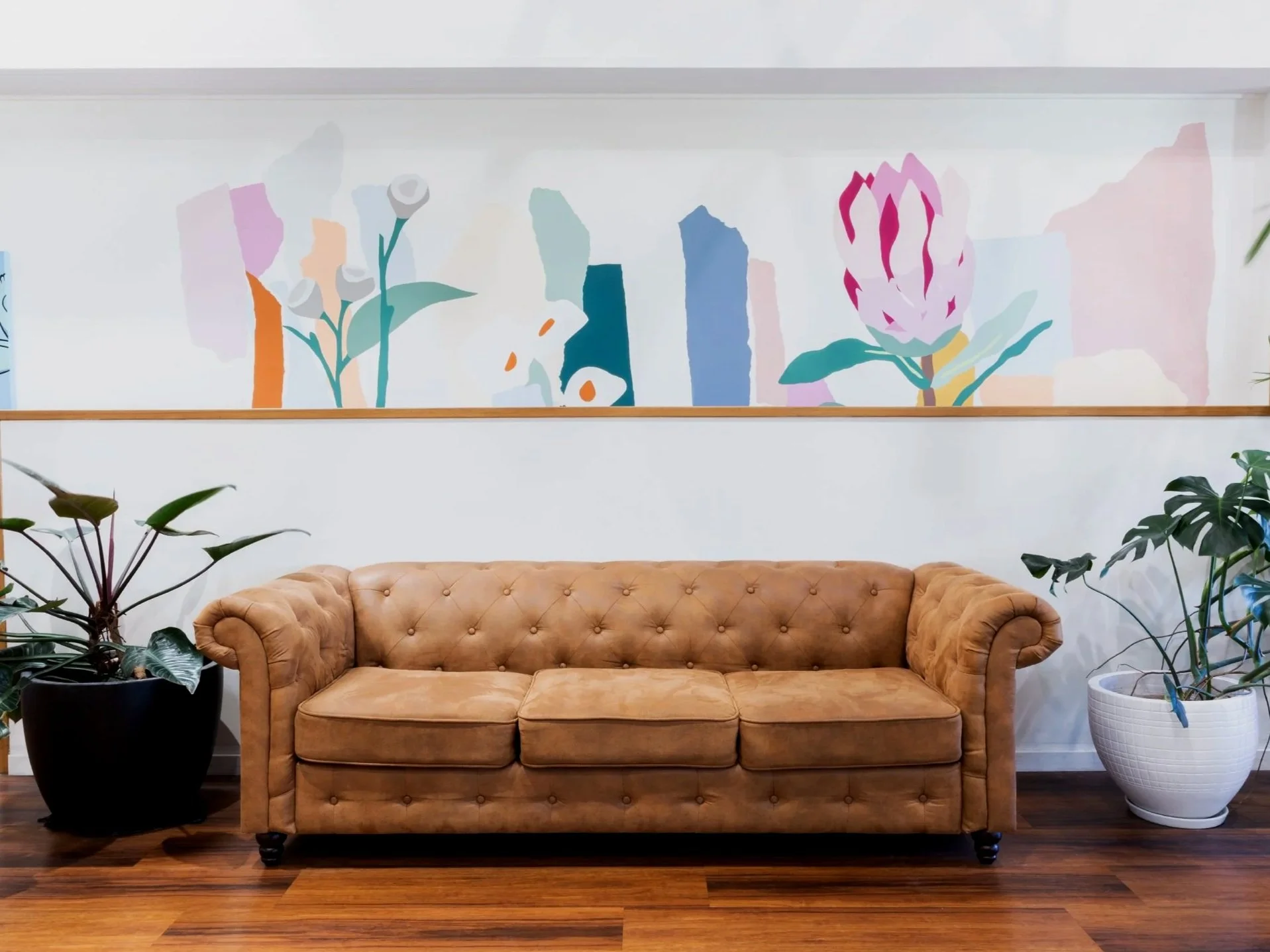 Leather sofa beneath colourful local artwork in the Maverick Hair Salon waiting area