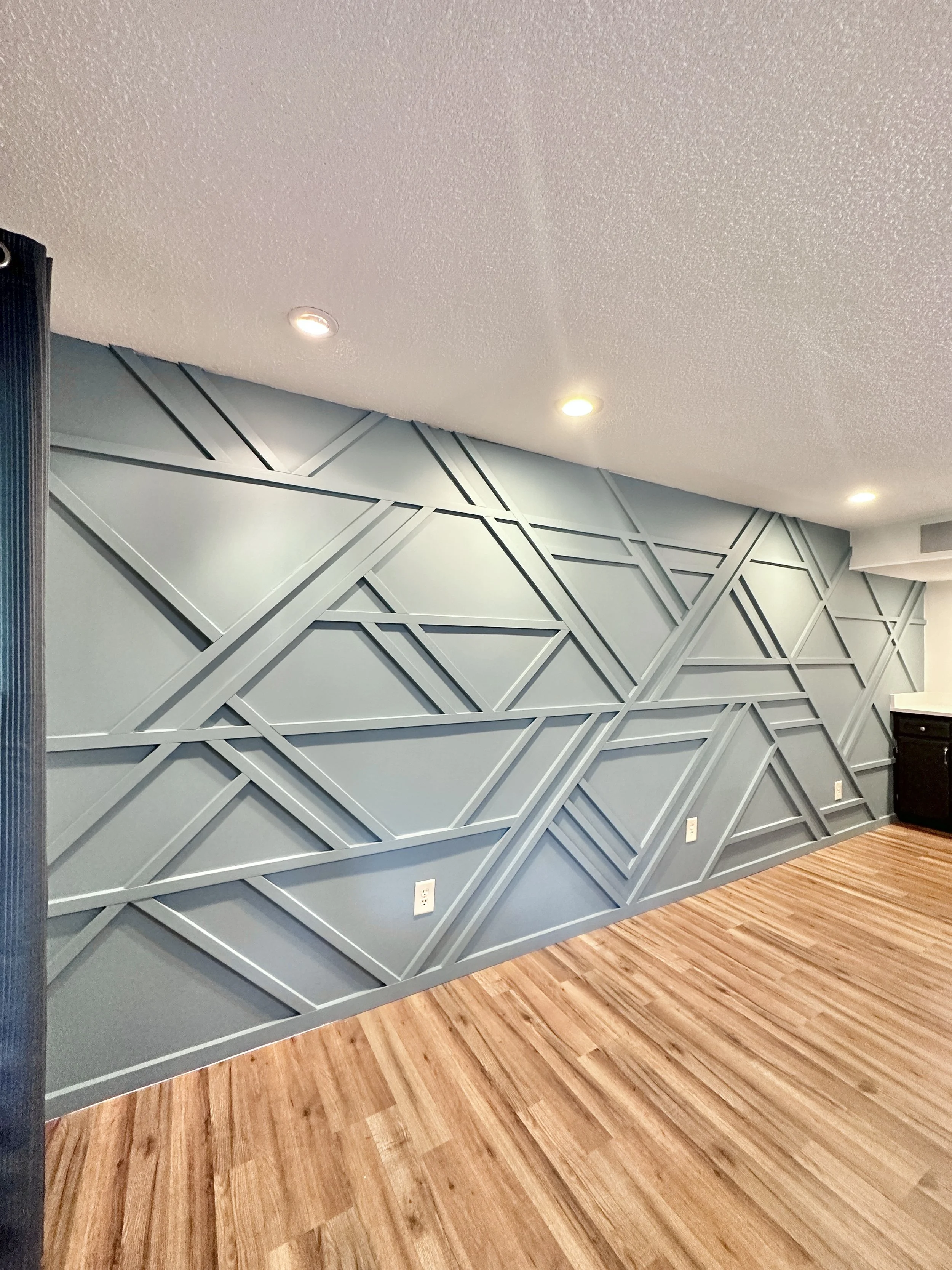 Wall with a geometric pattern made of intersecting lines and shapes painted in teal.
