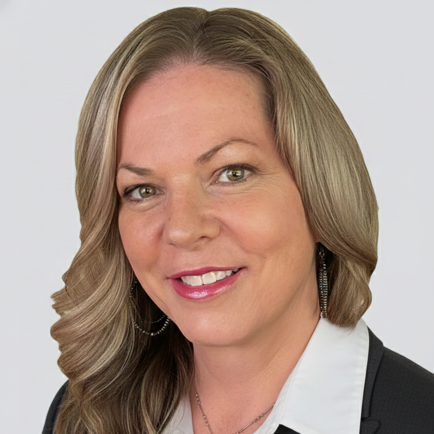 A woman with long, wavy blonde hair, green eyes, and light skin, smiling and wearing a black top, a necklace with a cross and other charms, and earrings.