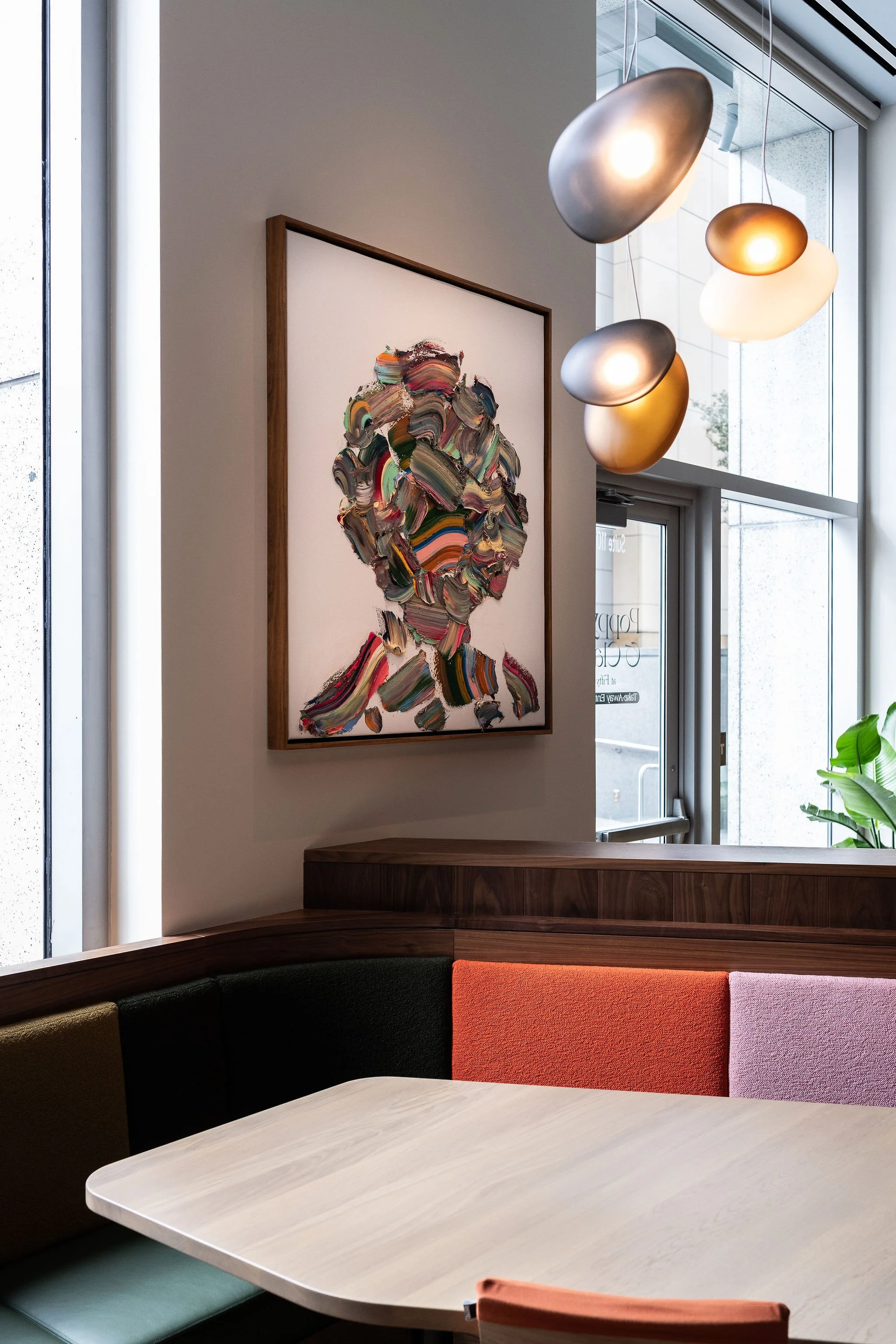 A large, textured abstract painting with thick impasto brushstrokes hanging near a window, paired with a modern spherical gold light fixture.