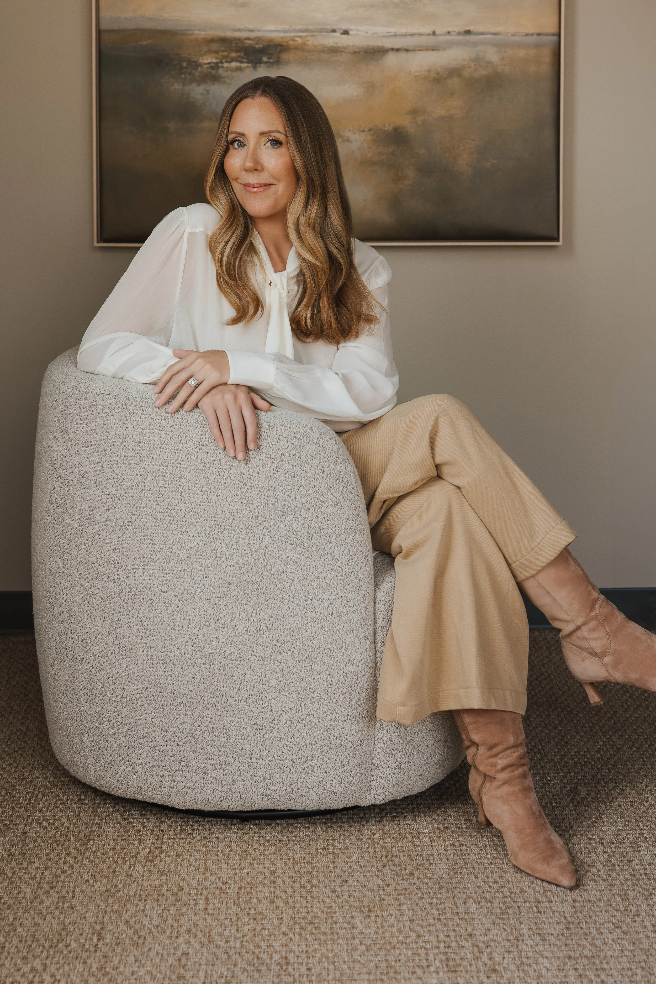 Nicole Hitchcock sitting beneath a contemporary abstract painting.