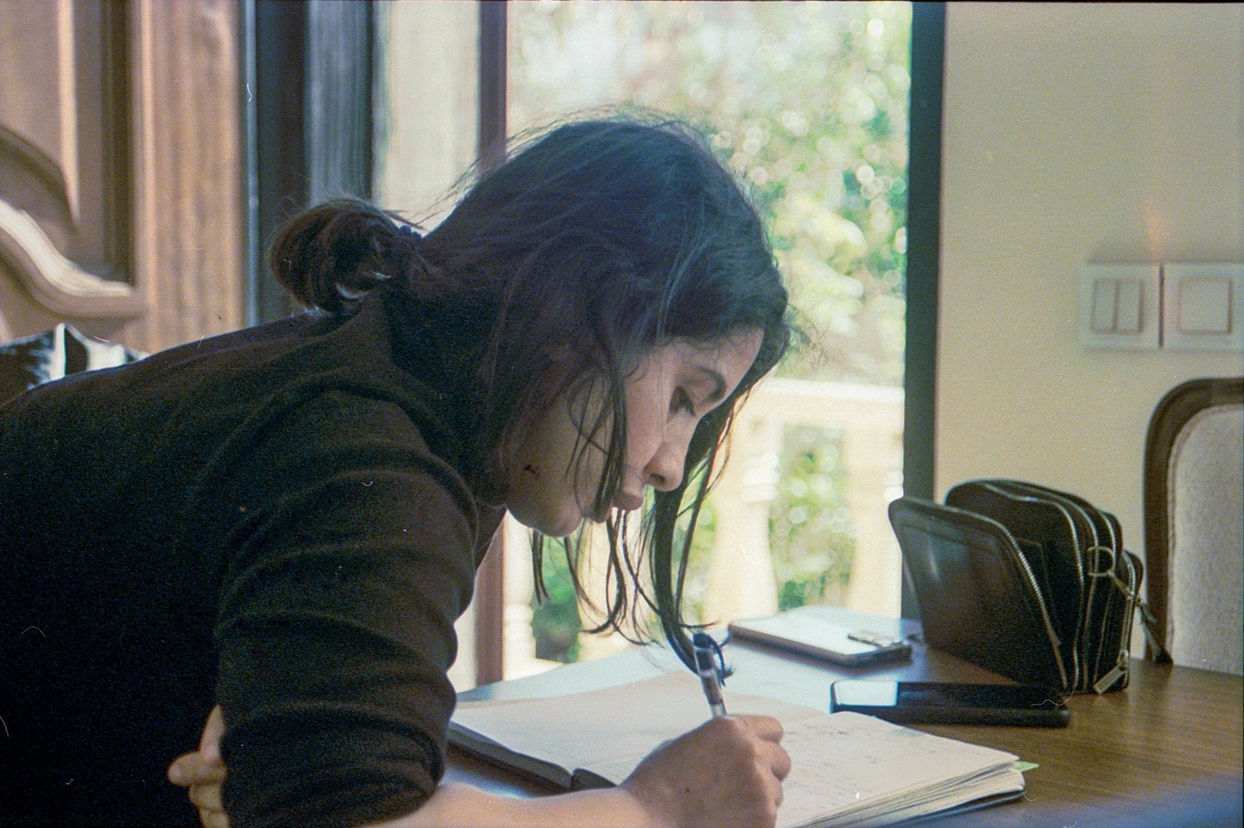 Young woman with brown hair writing in her journal.