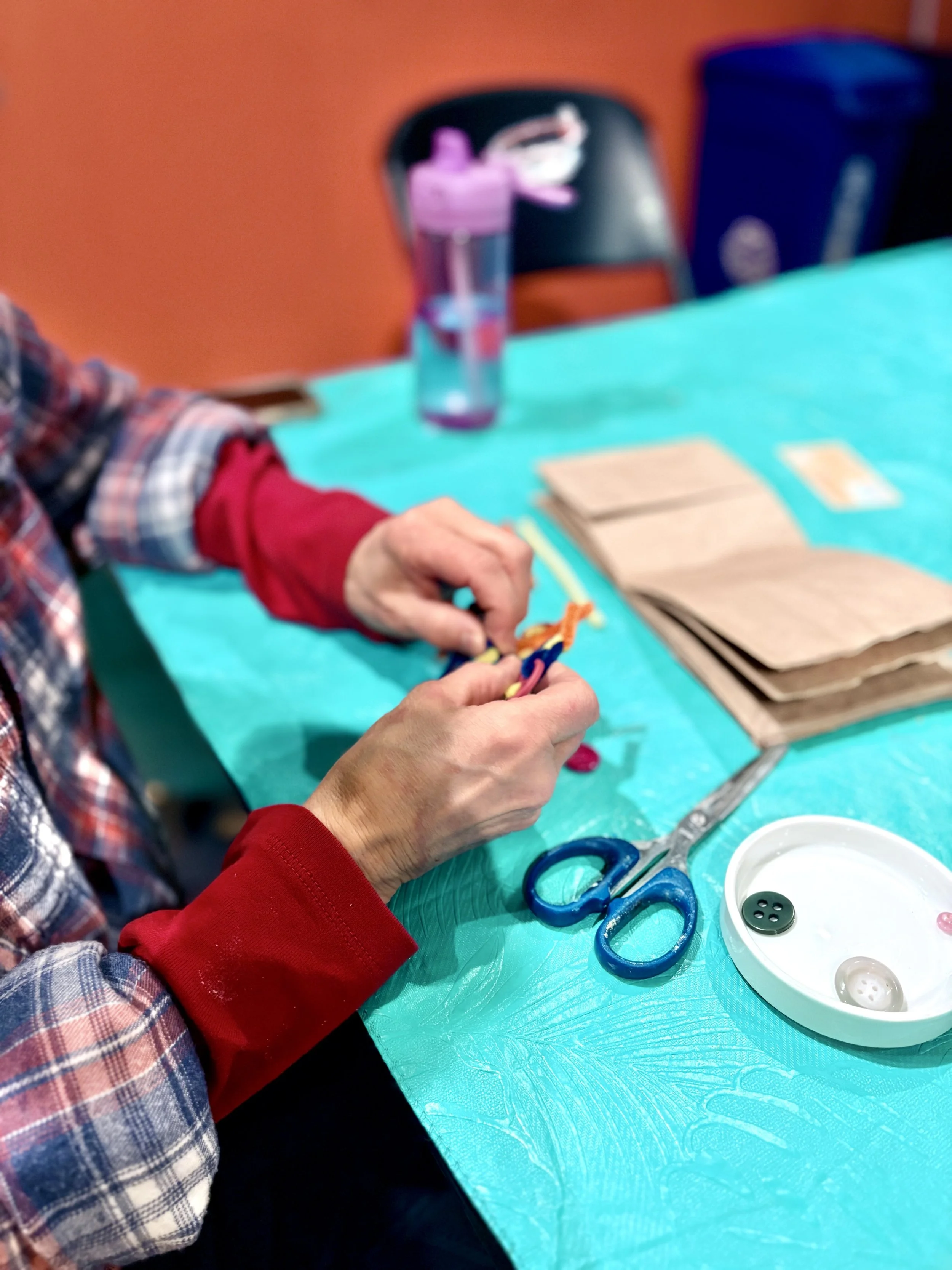 Hands twisting colorful pipe cleaners as part of an intuitive art-making activity at ArtFull Thursdays, a free monthly expressive arts circle at Manitou Art Center.