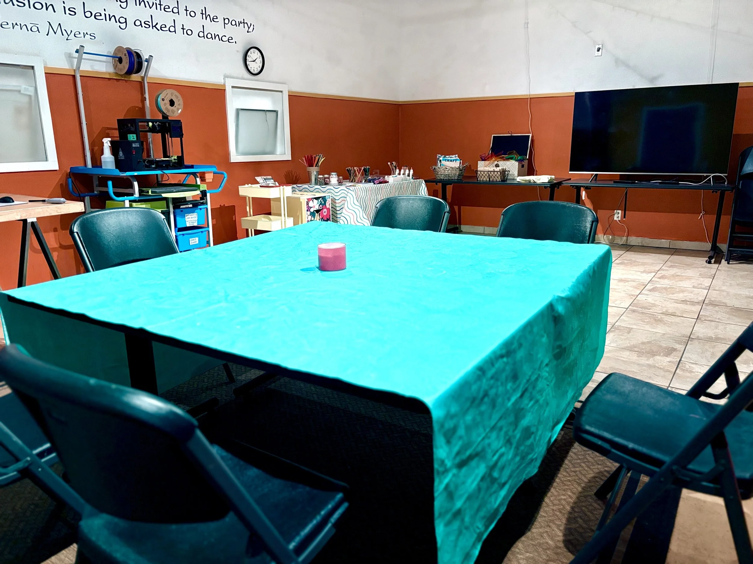 Empty seating area with a teal tablecloth, set up for an ArtFull Thursdays session at Manitou Art Center.