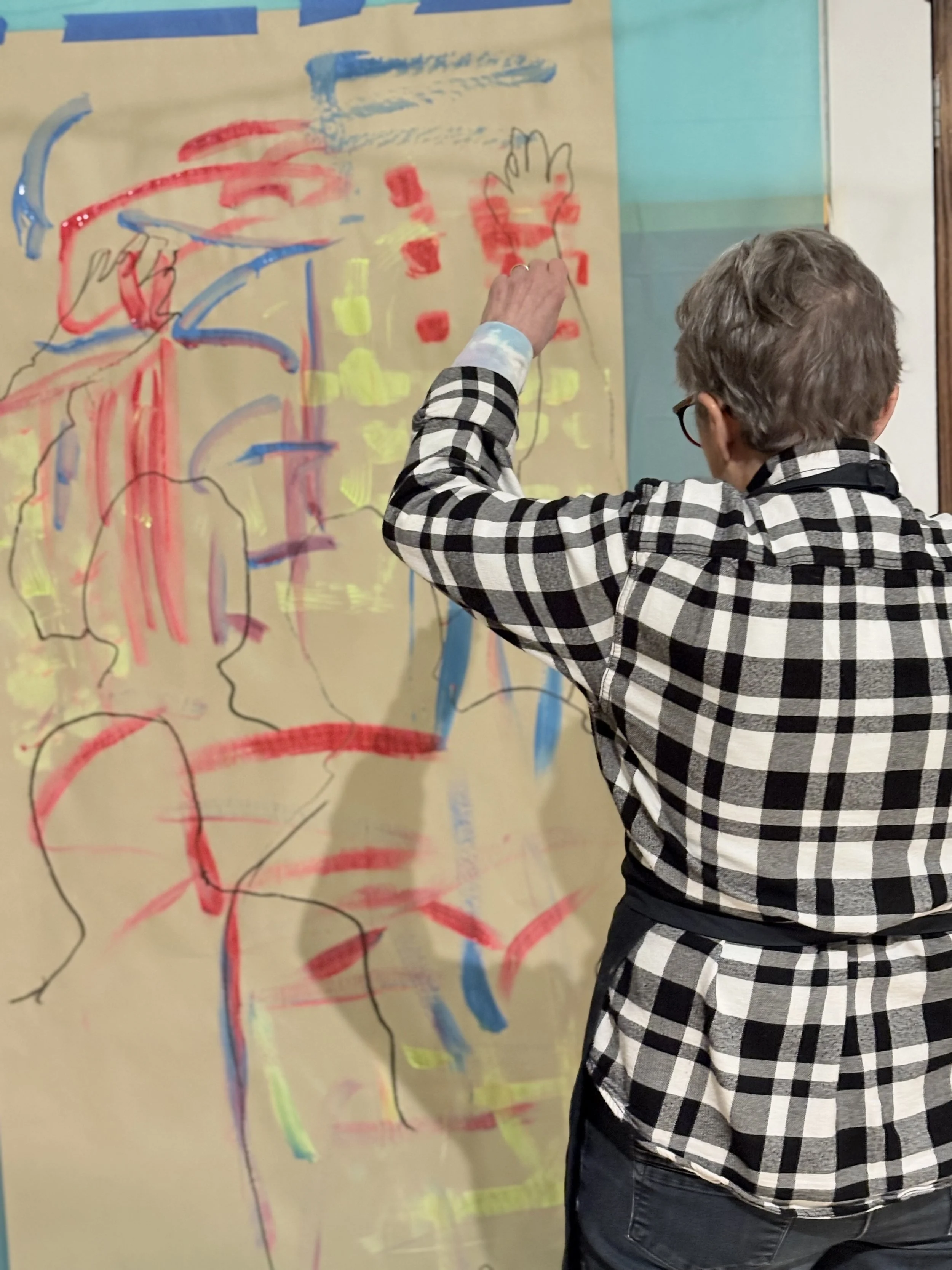 Participant painting a life-size figure outline on a large canvas during ArtFull Thursdays at Manitou Art Center.