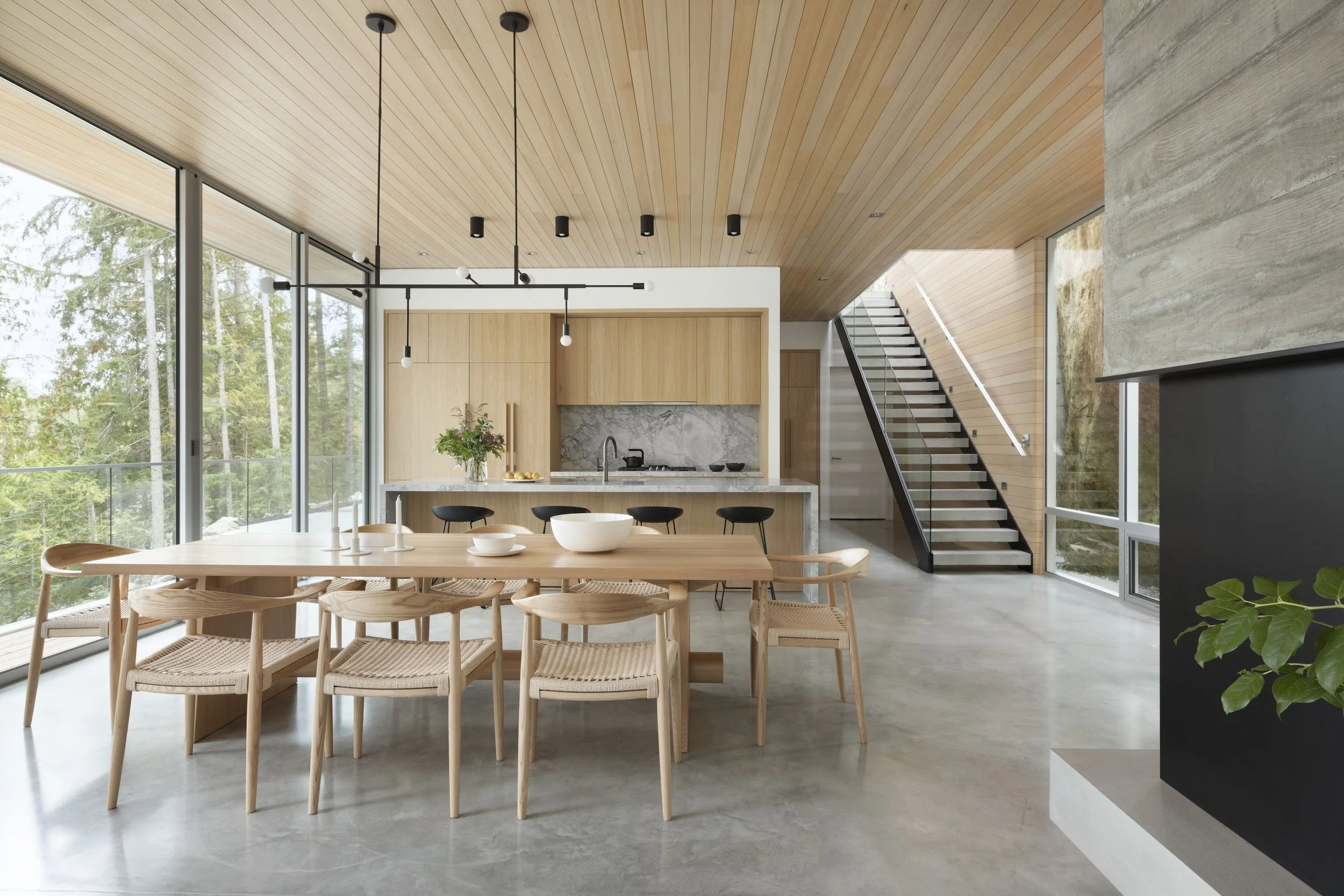 Modern open-concept kitchen and dining area with large glass windows, light wood accents, and minimalist decor.