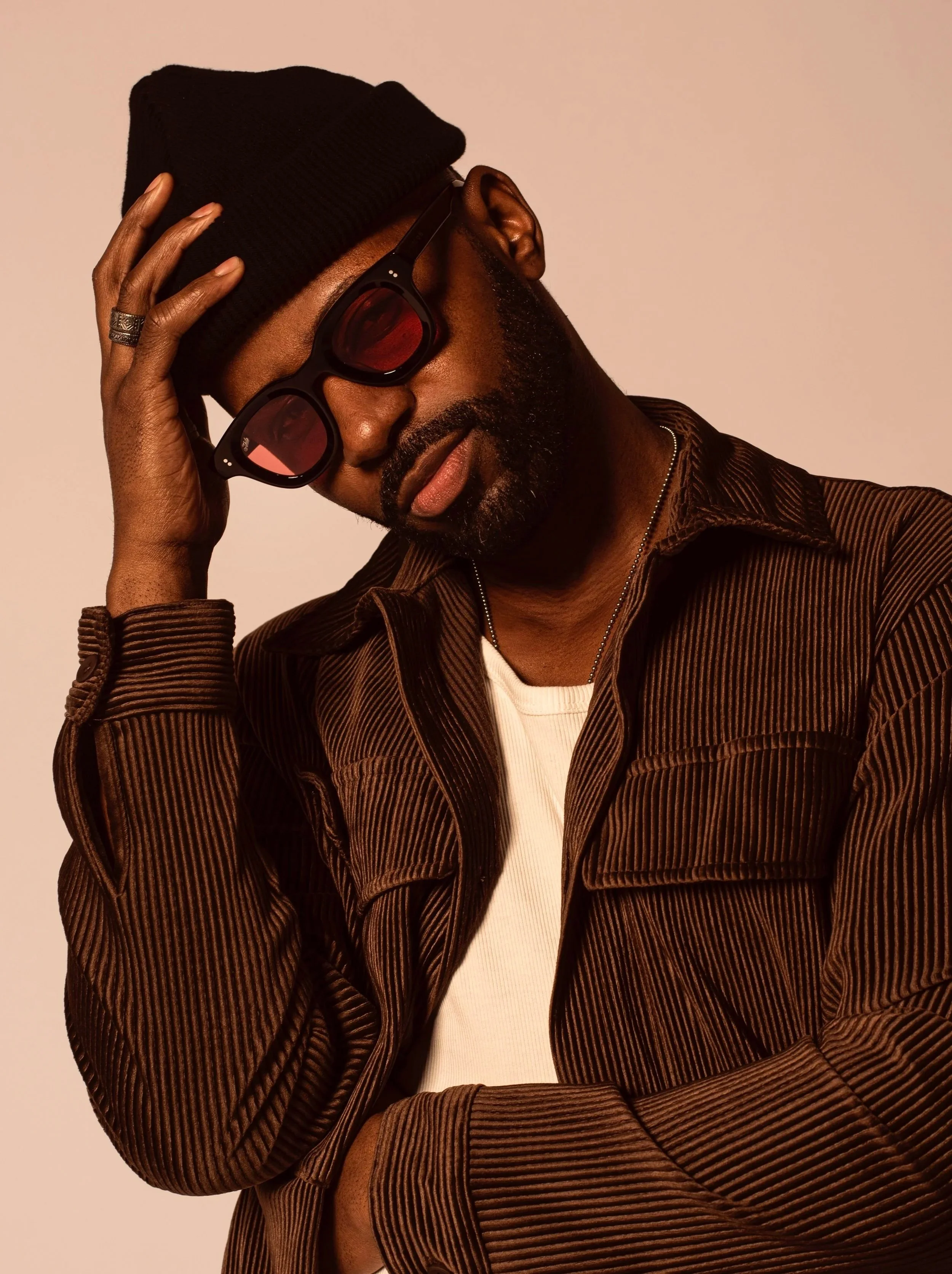 Portrait of Justin D. Key wearing a black hat, sunglasses, and brown jacket.