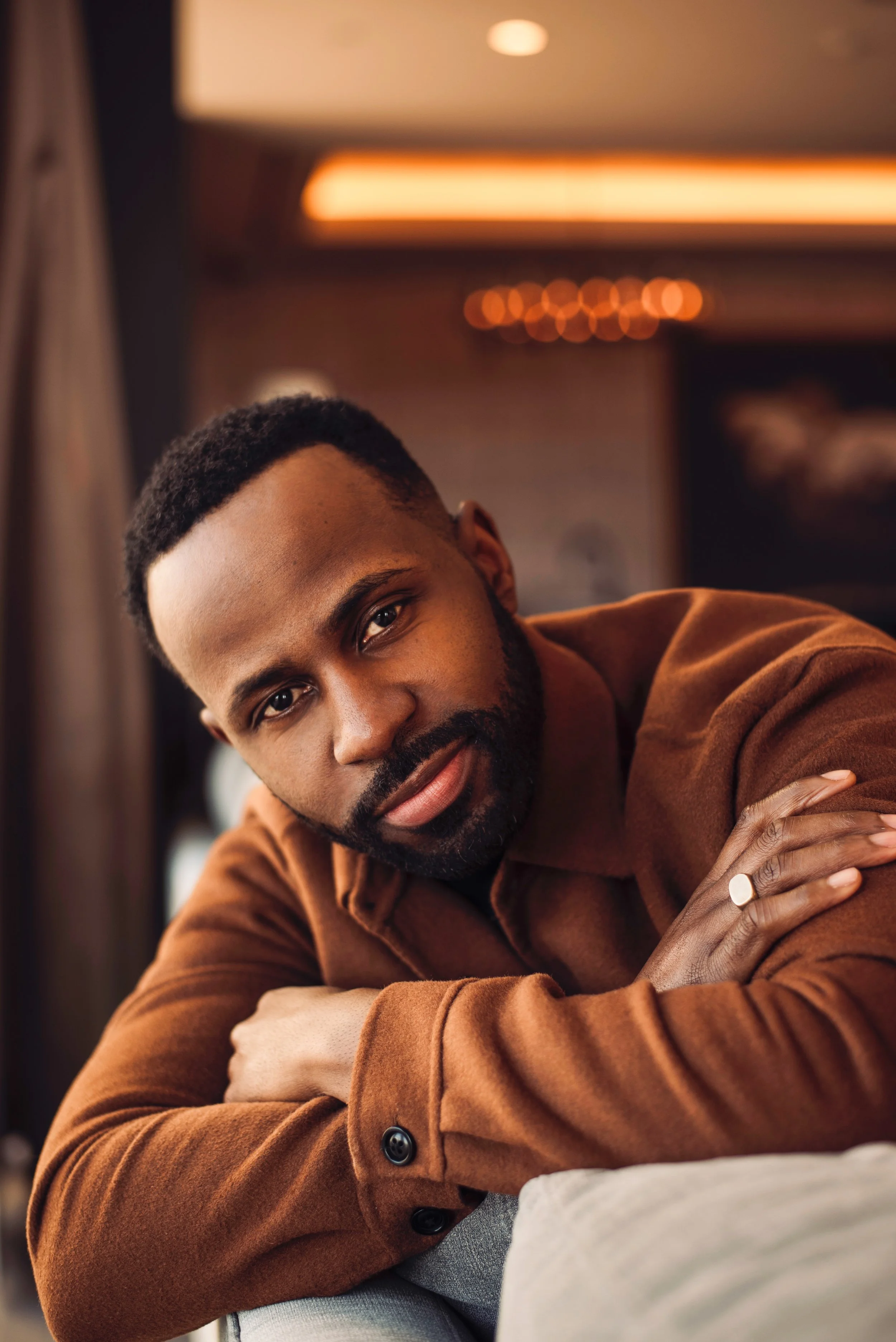 Portrait of Justin D. Key wearing a brown sweater and leaning forward toward the camera.