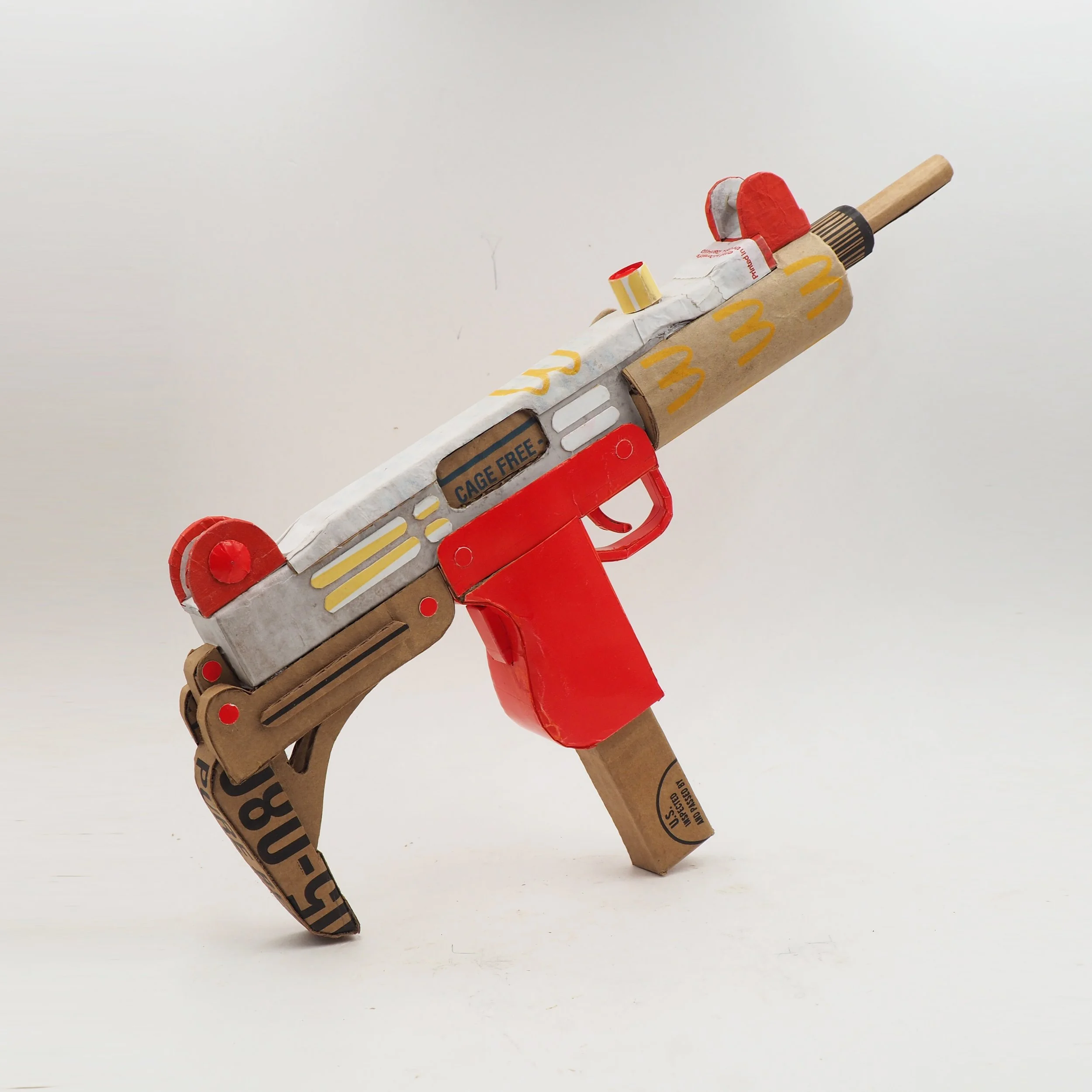 Mass shooting cardboard Uzi recycled material art sculpture political action McDonalds corporate culture parody