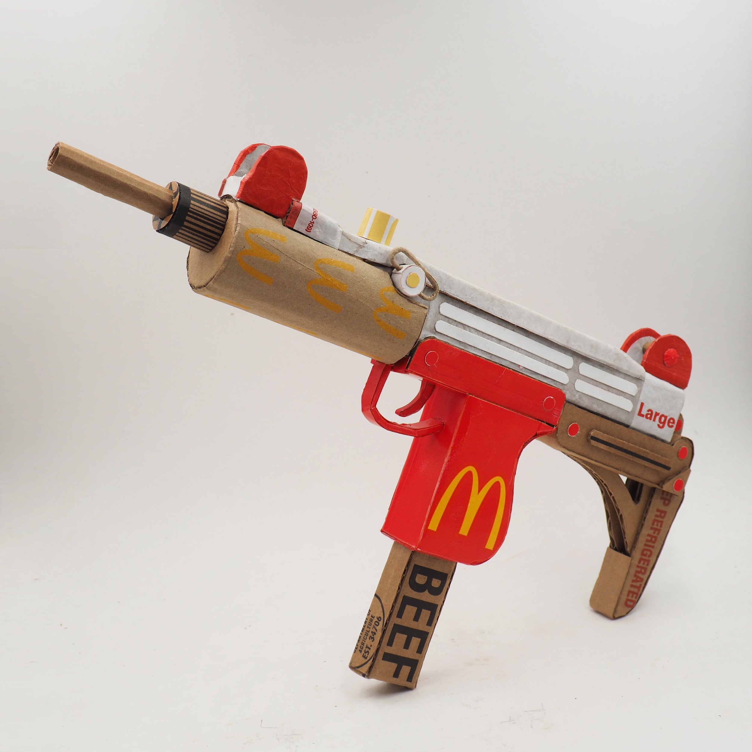 Mass shooting cardboard recycled material art sculpture political action fast food Uzi parody
