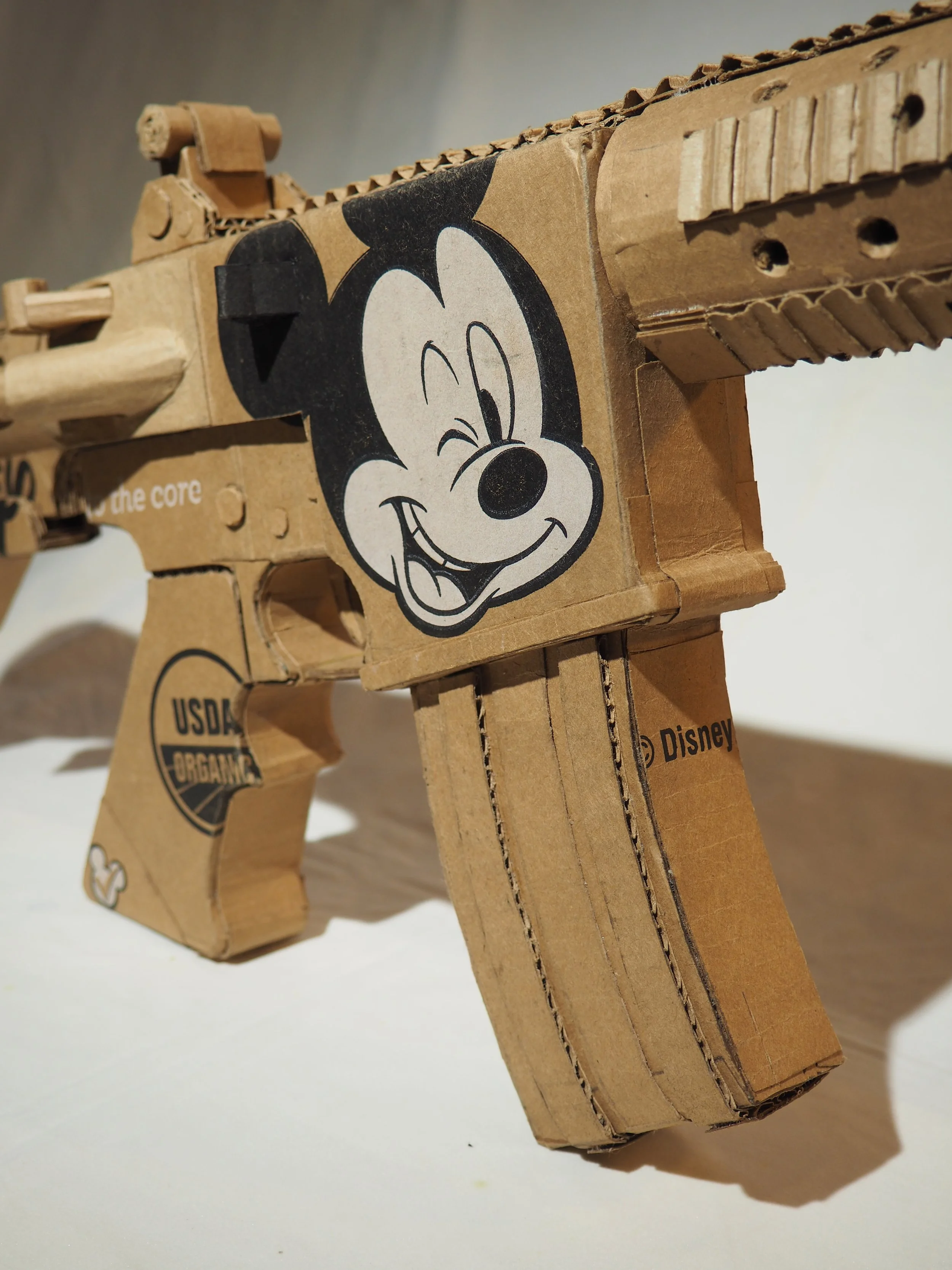 Disney Mickey Mouse corporate satire Florida mass shooting cardboard recycled material art sculpture political action parody