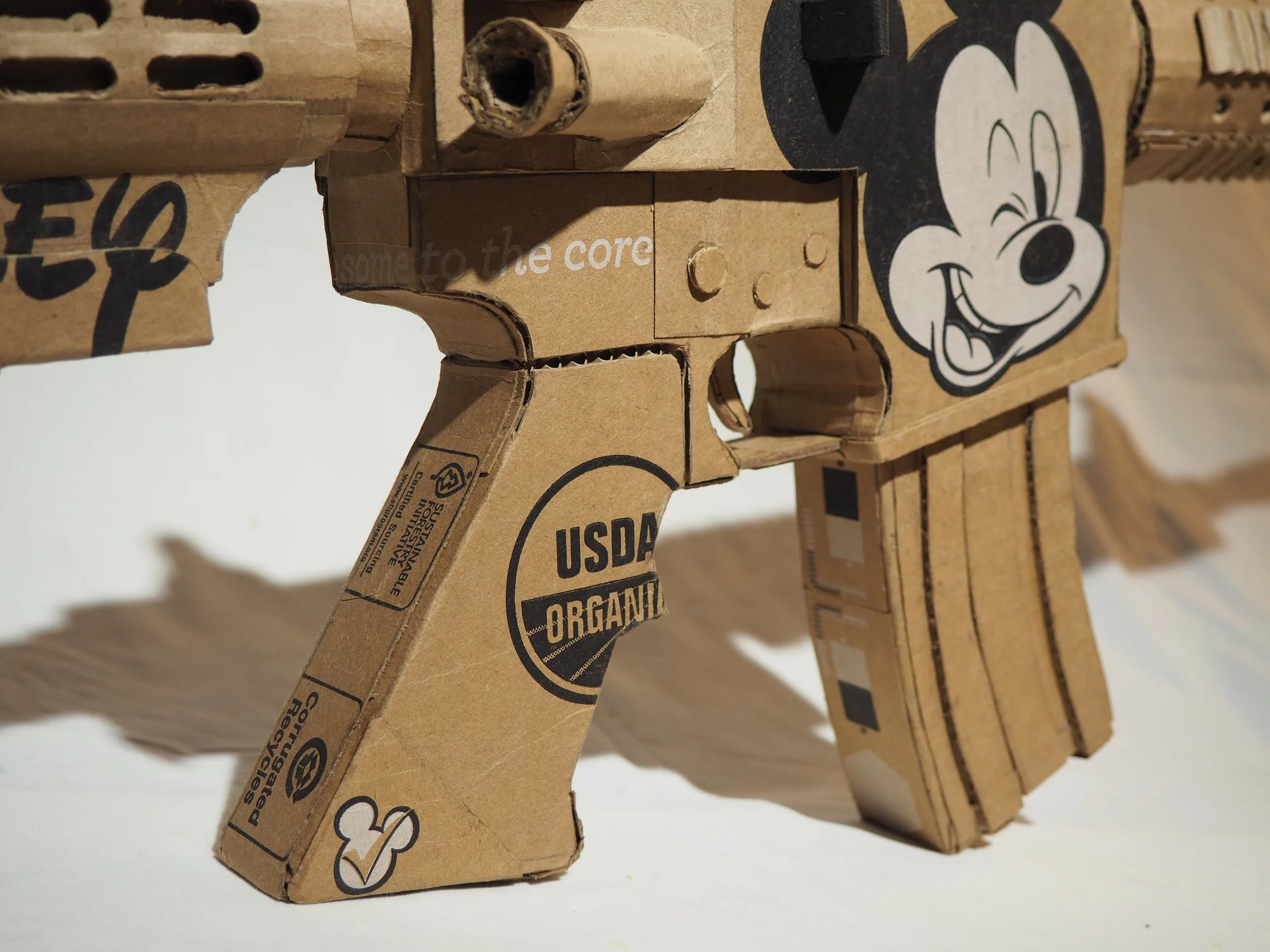 Disney Mickey Mouse anti-capitalist satire Florida mass shooting cardboard recycled material art sculpture political action lampoon send-up
