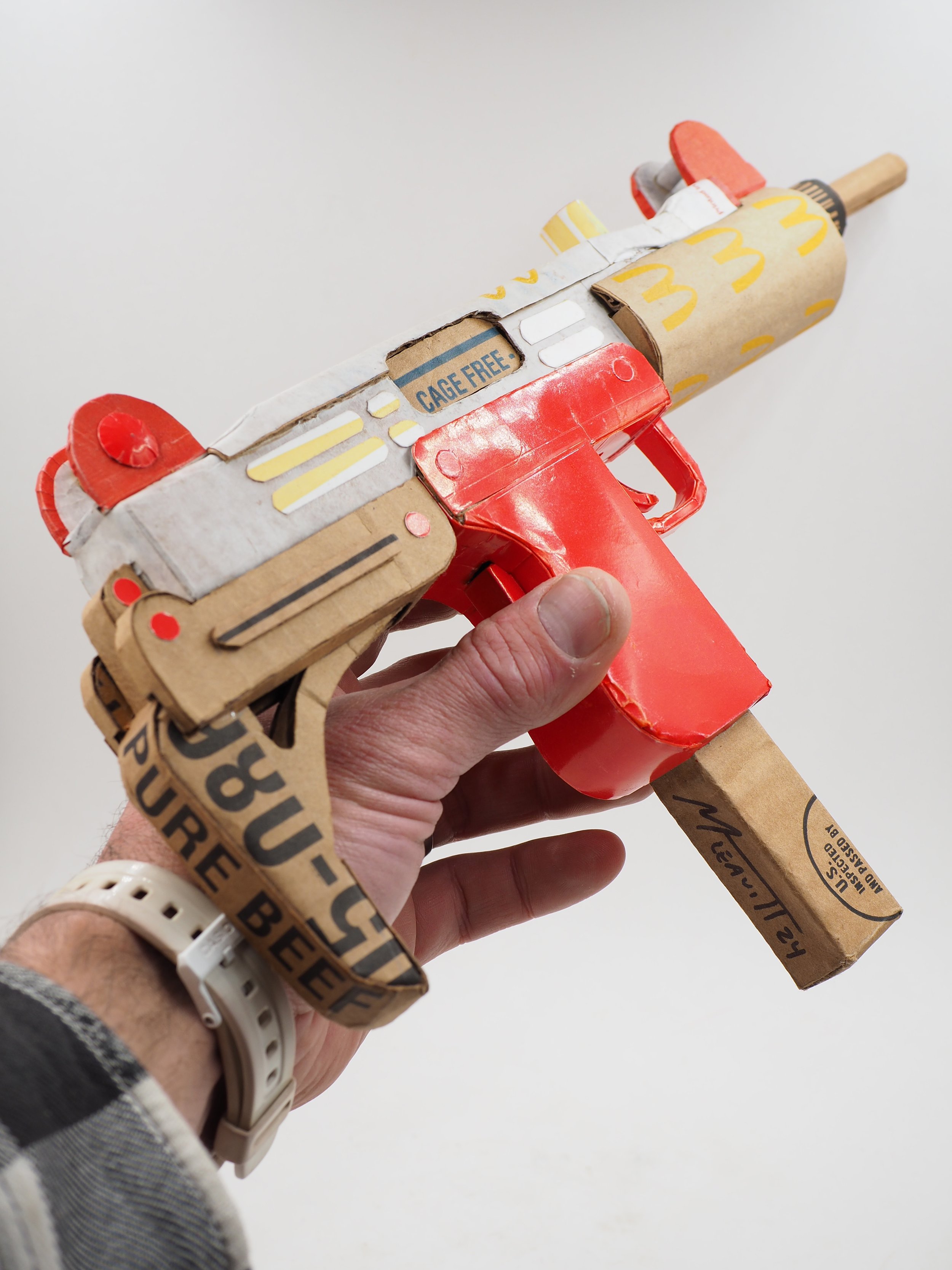 Mass shooting cardboard Uzi recycled material art sculpture political action McDonalds corporate culture parody