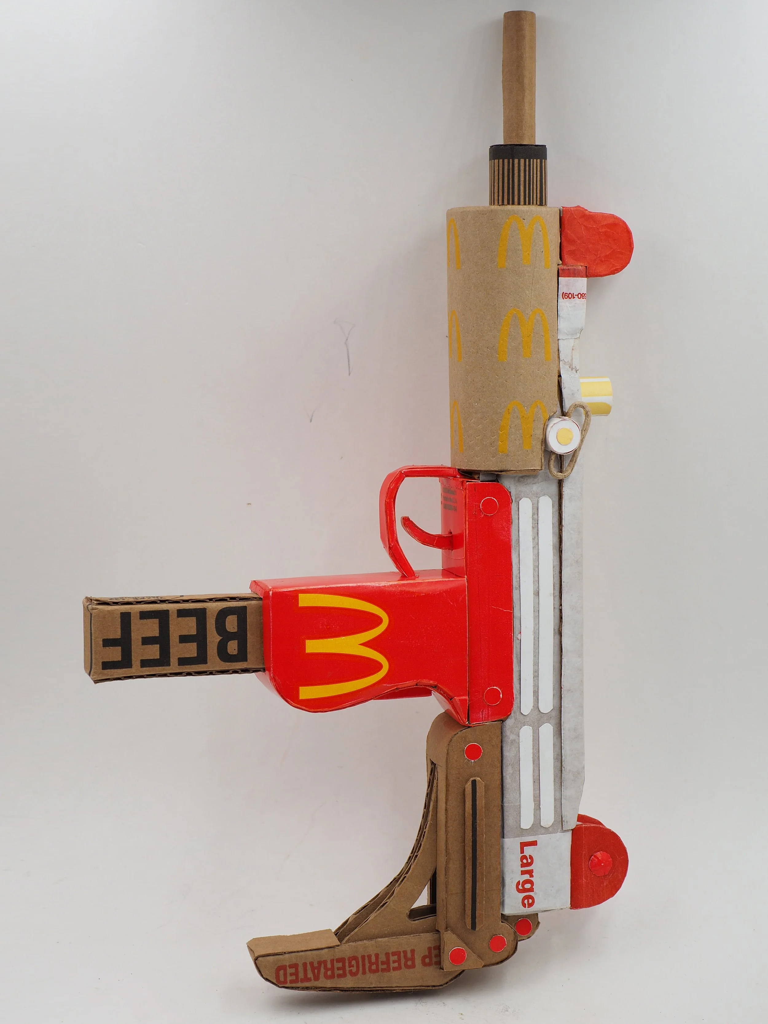 Mass shooting cardboard recycled material art sculpture political action McDonalds fast food corporate product satire
