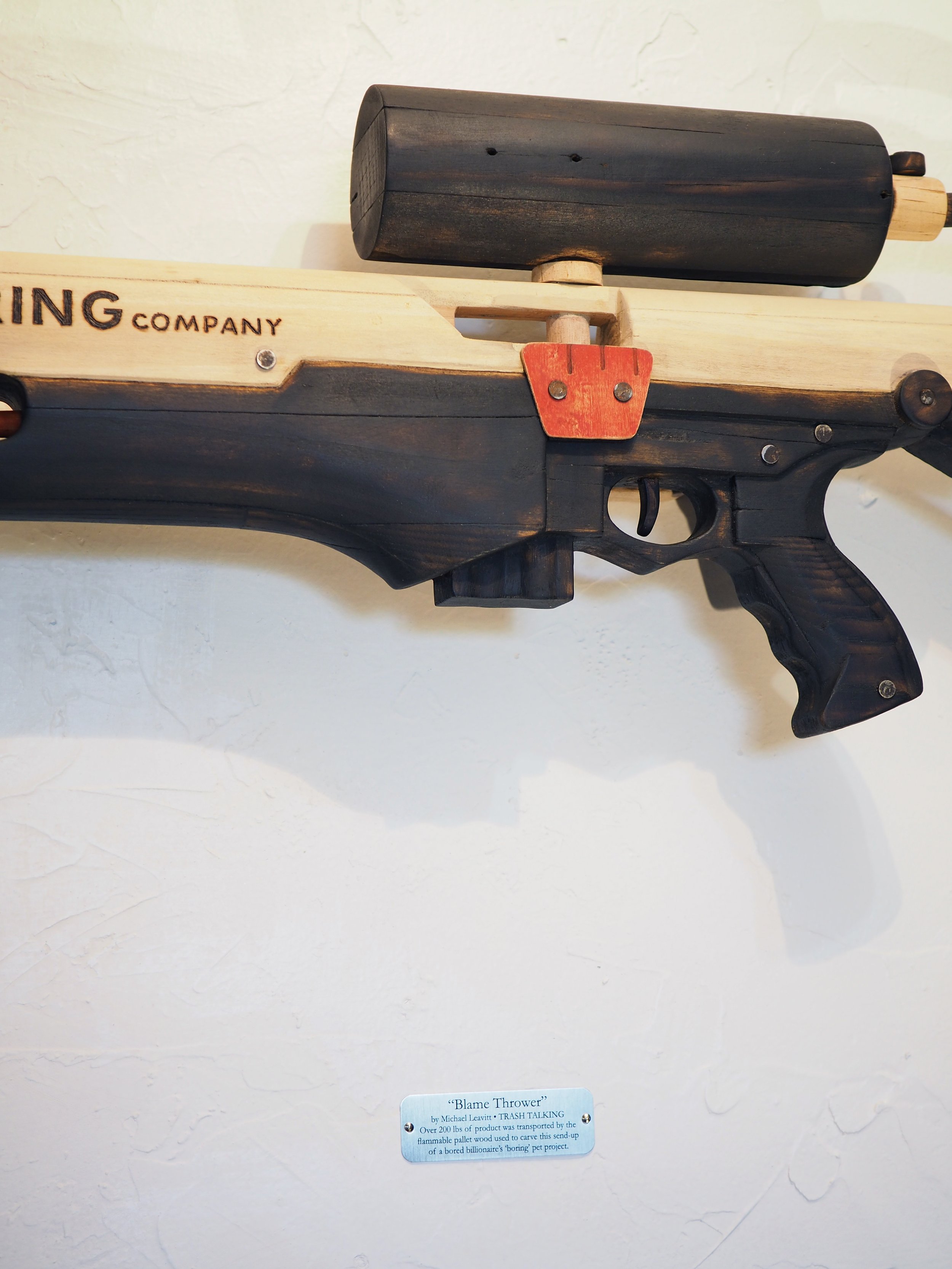 Elon Musk Boring Company flame thrower Twitter X Tesla corporate culture anti-capitalist woodworking wood sculpture recycled reclaimed pallet wood satire celebrity parody art