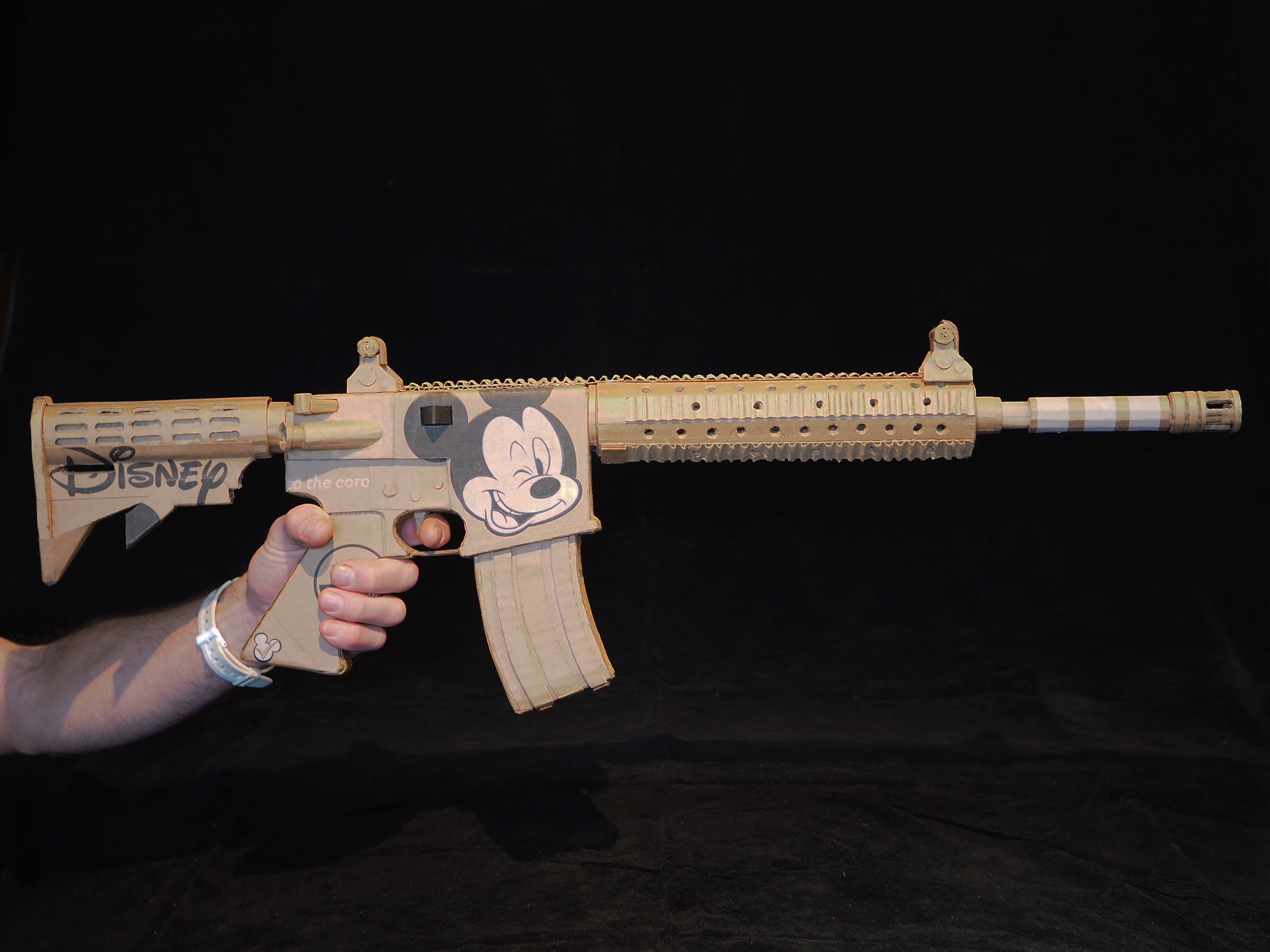 Disney Mickey Mouse anti-capitalist satire Florida mass shooting cardboard recycled material art sculpture political action parody