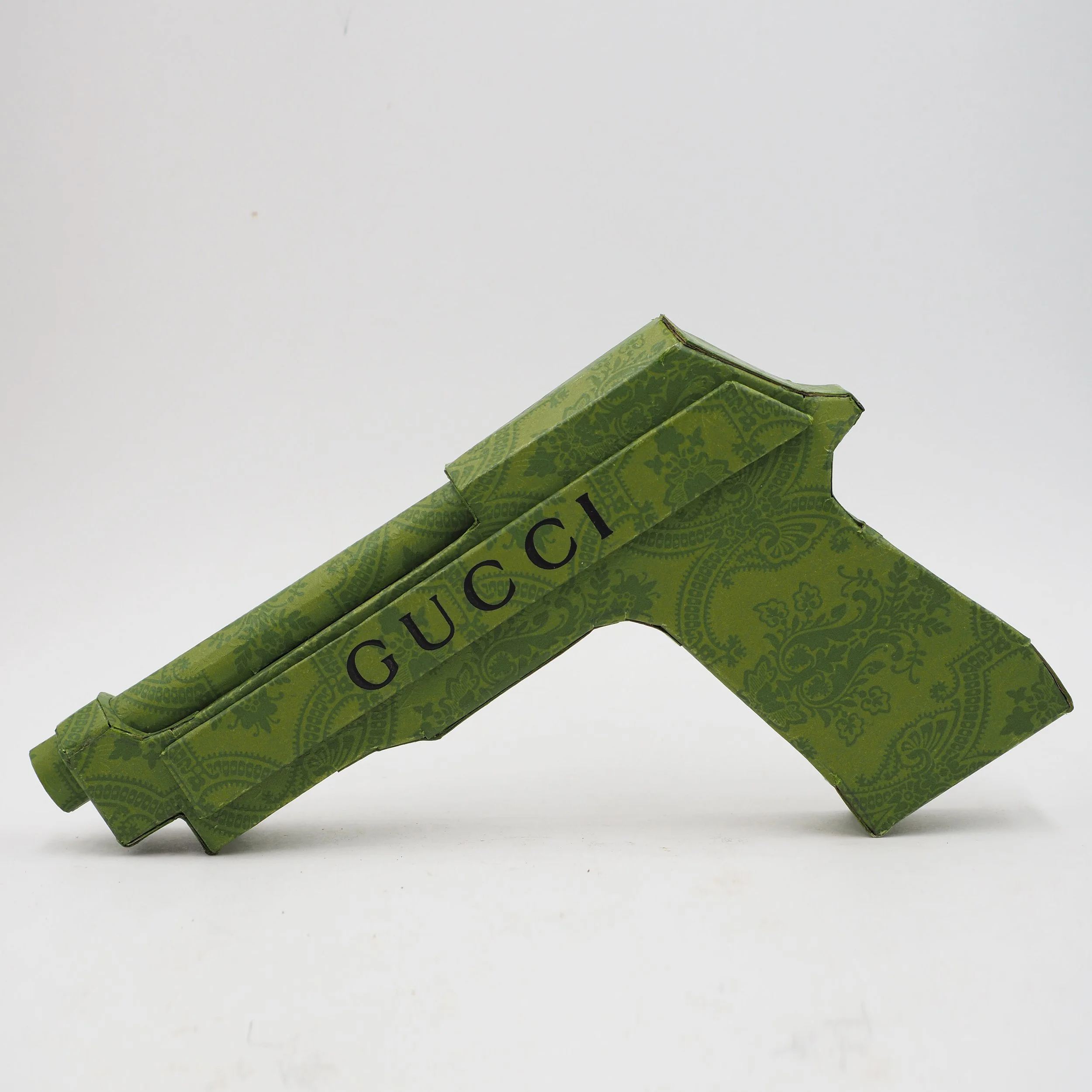 Gucci Beretta pistol Italy recycled cardboard waste packaging high fashion luxury brand comedy satire parody lampoon art sculpture