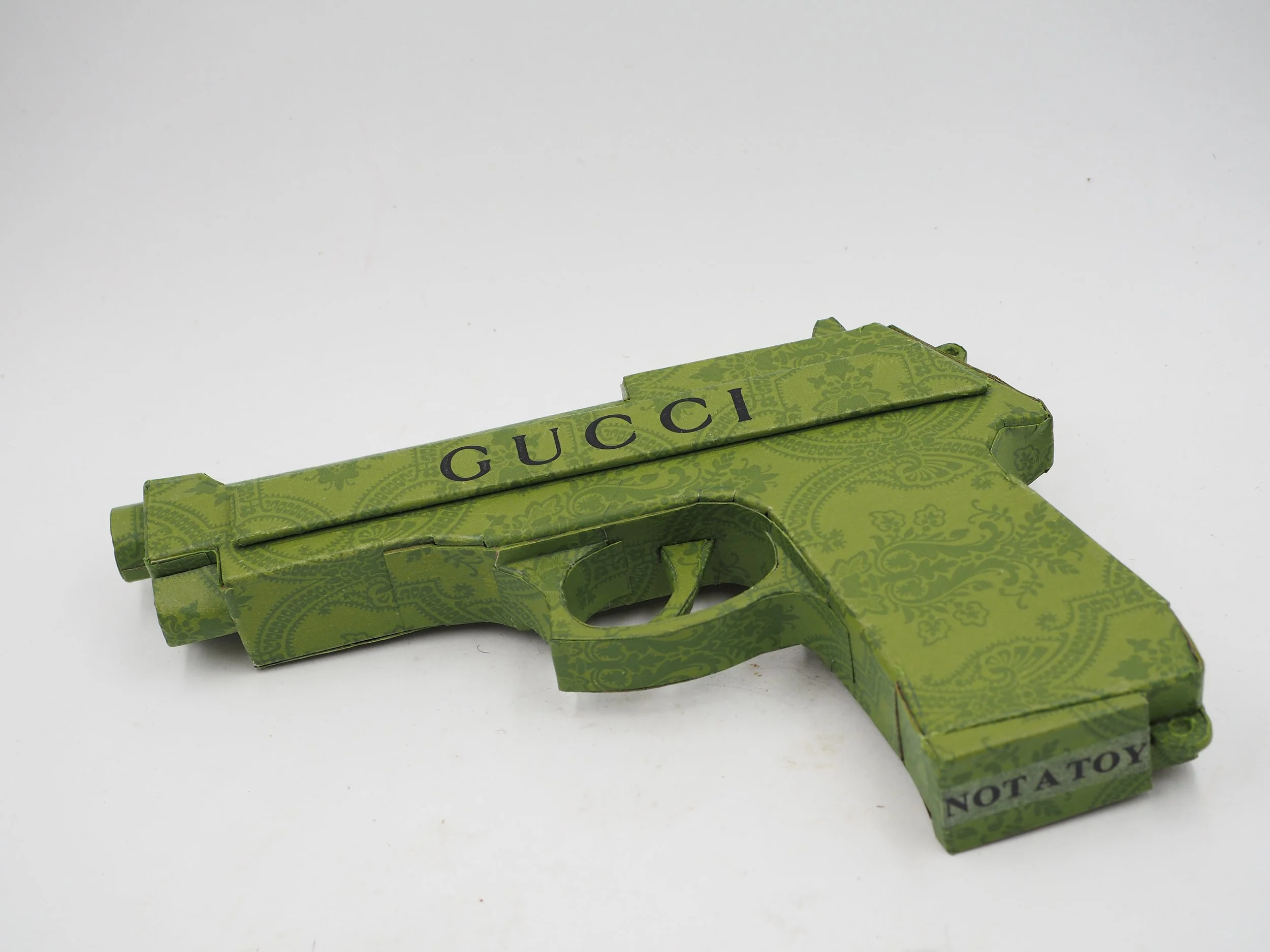 Gucci Beretta pistol Italy recycled cardboard waste packaging high fashion luxury brand comedy satire parody lampoon art sculpture