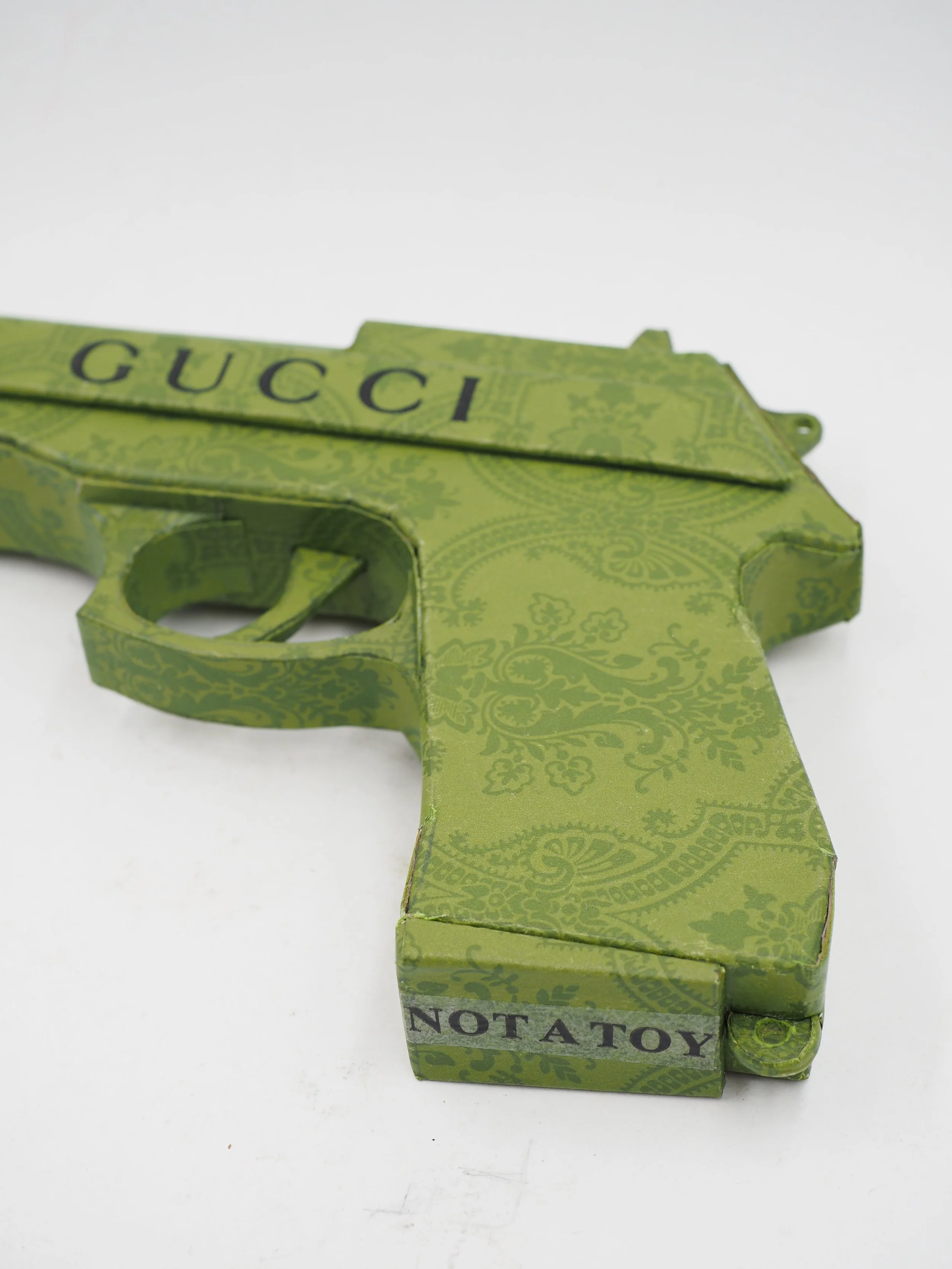 Gucci Beretta pistol Italy recycled cardboard waste packaging high fashion luxury brand comedy satire parody lampoon art sculpture