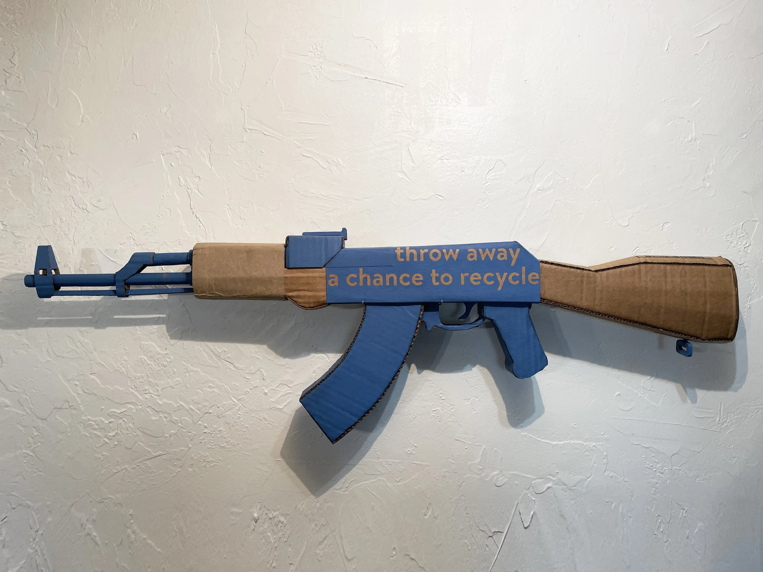 Walmart corporate satire El Paso Texas mass shooting cardboard recycled material art sculpture political action parody