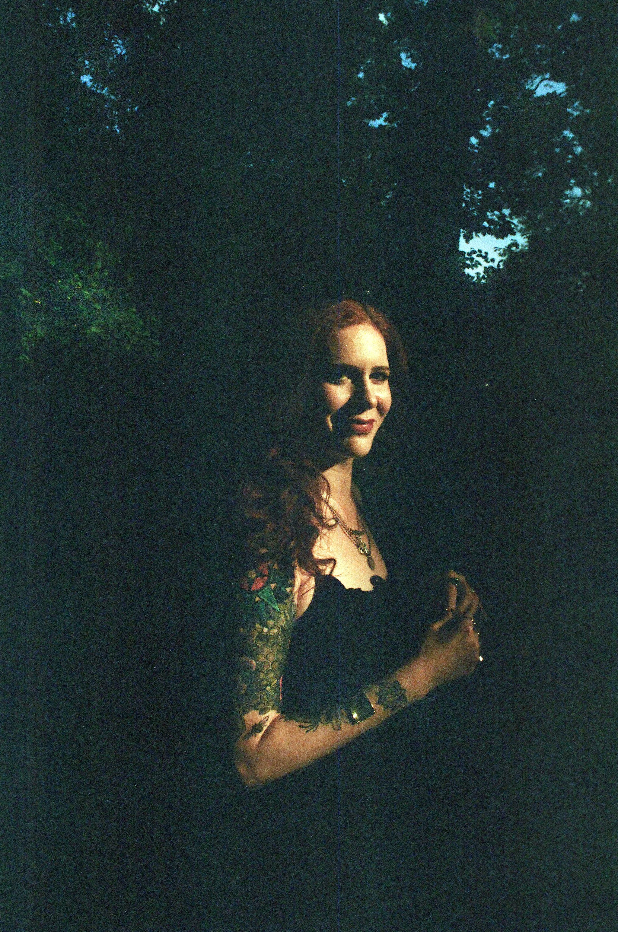 Jen Ciraulo, tarot reader and intuitive healer, smiling among dark green trees