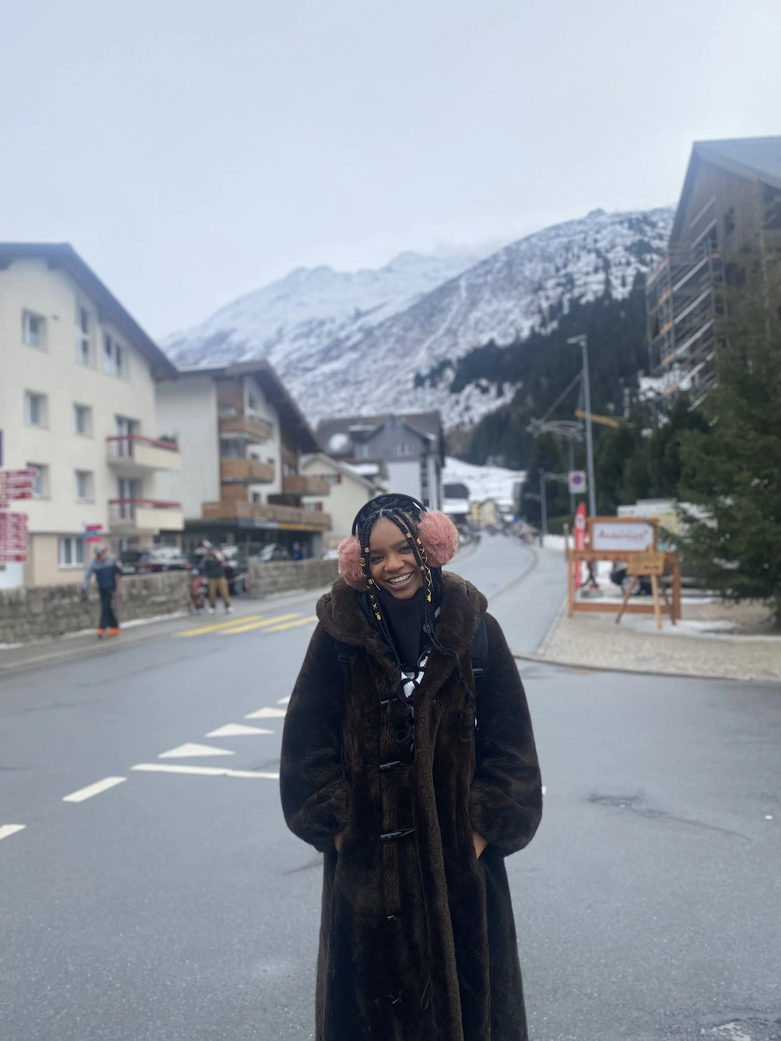 Woman standing in Swiss town in front of a mountain