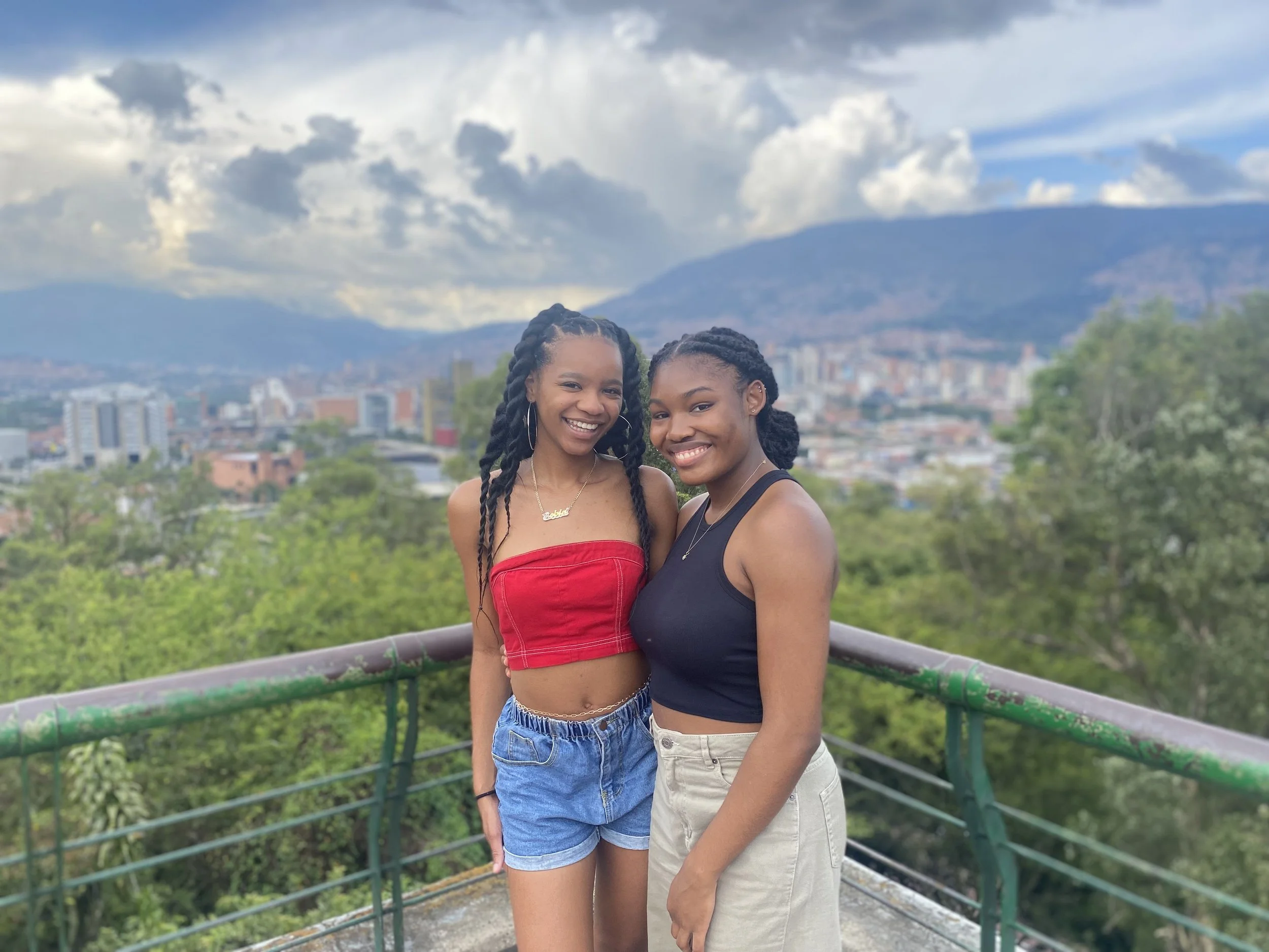 Two black friends standing next to each other with Medellín landscape as the backdrop