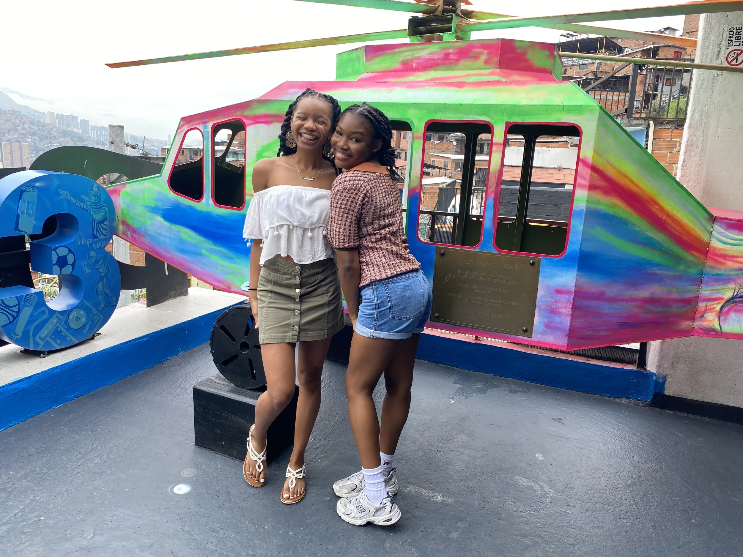Two black friends standing in front of a helicopter in Medellin, Colombia.
