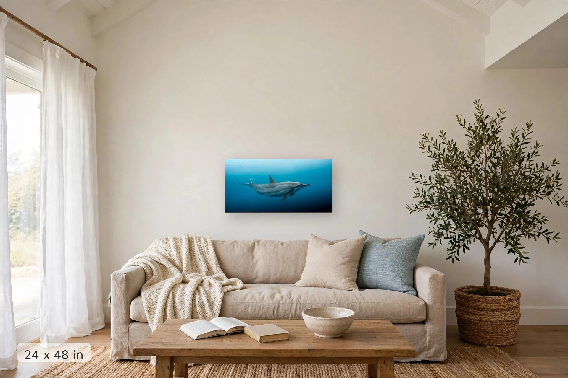 A spinner dolphin blowing bubbles underwater — Naia Bubbles print, 32x48 mockup above a living room sofa
